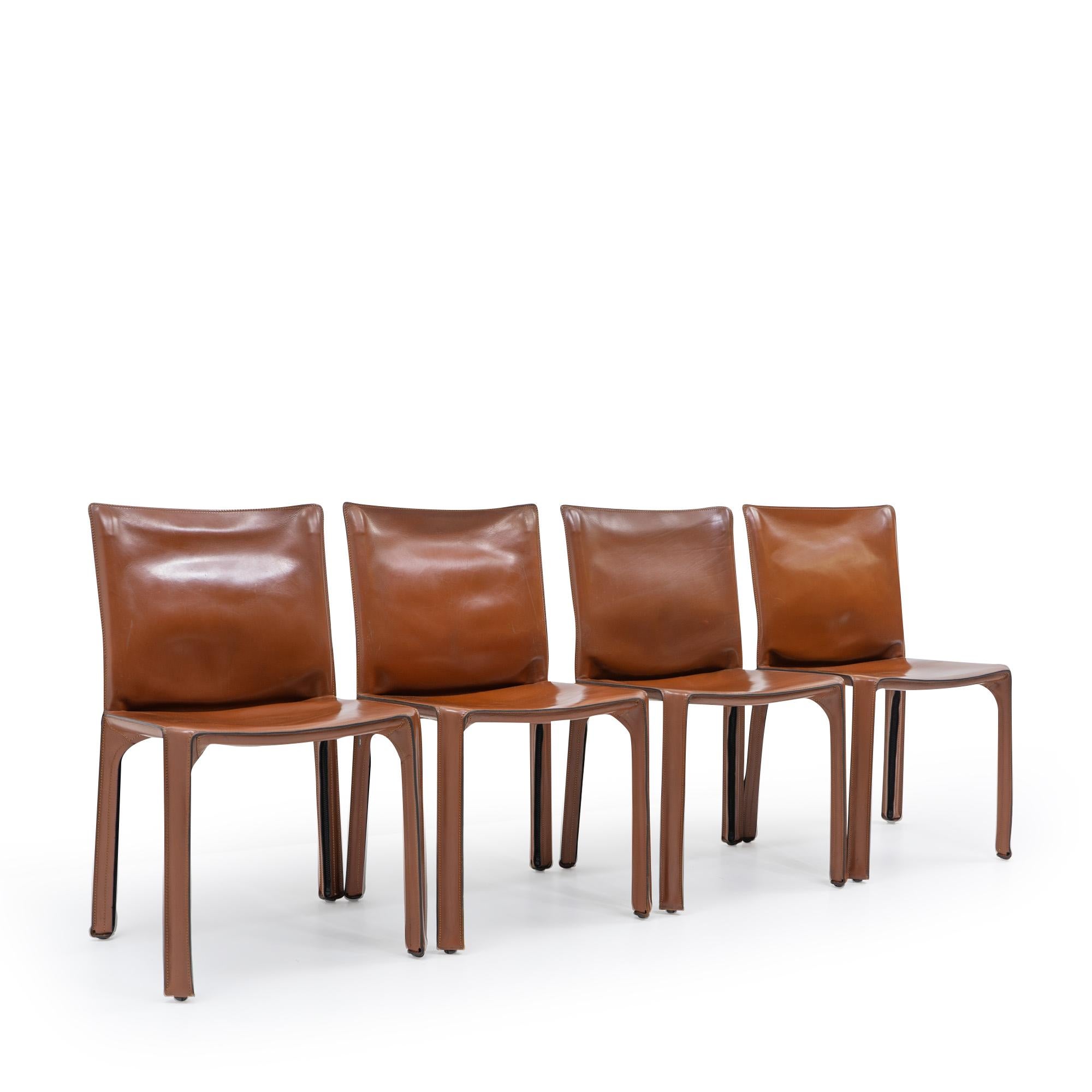 Set of four Cab 412 side chairs in red-brown leather by Mario Bellini for Cassina.

The Cab chair is built up as a tubular frame over which thick saddle leather is fitted; the leather skin is kept in place with zippers on the inside legs.

A