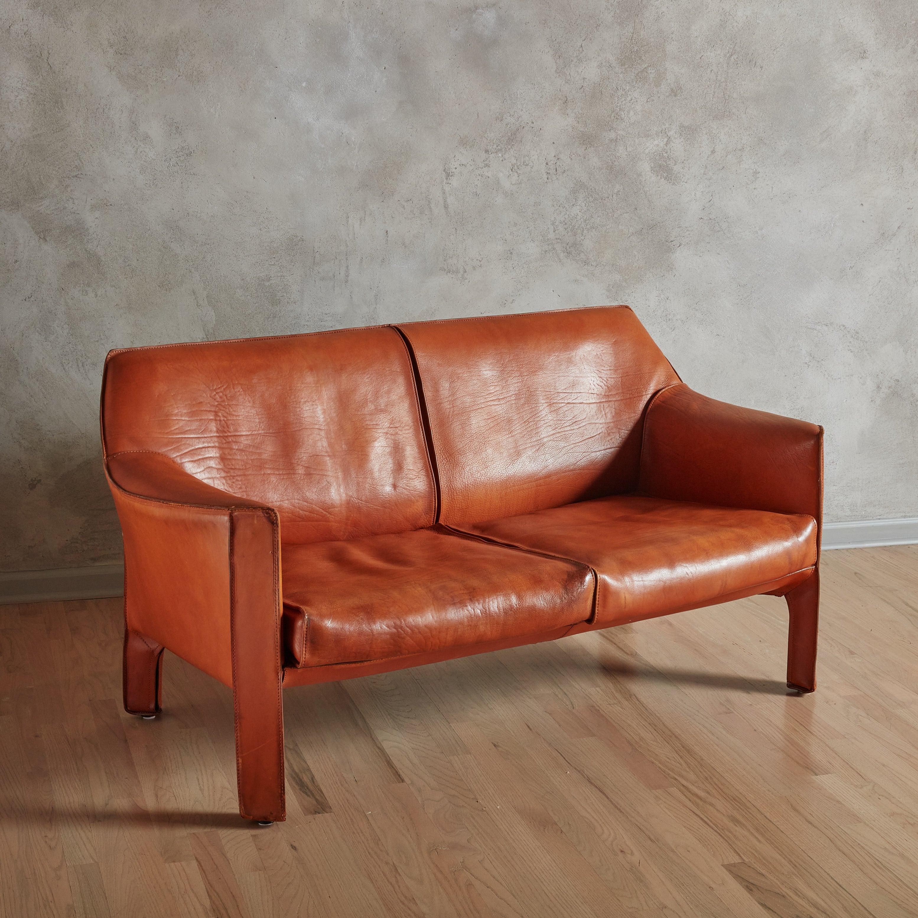 The 'Cab' loveseat by Mario Bellini, introduced in 1977 for Cassina, is a study in precision. High-quality saddle leather, cut and sewn with precision, is meticulously zippered and fastened to a steel frame like a tailored garment, giving the