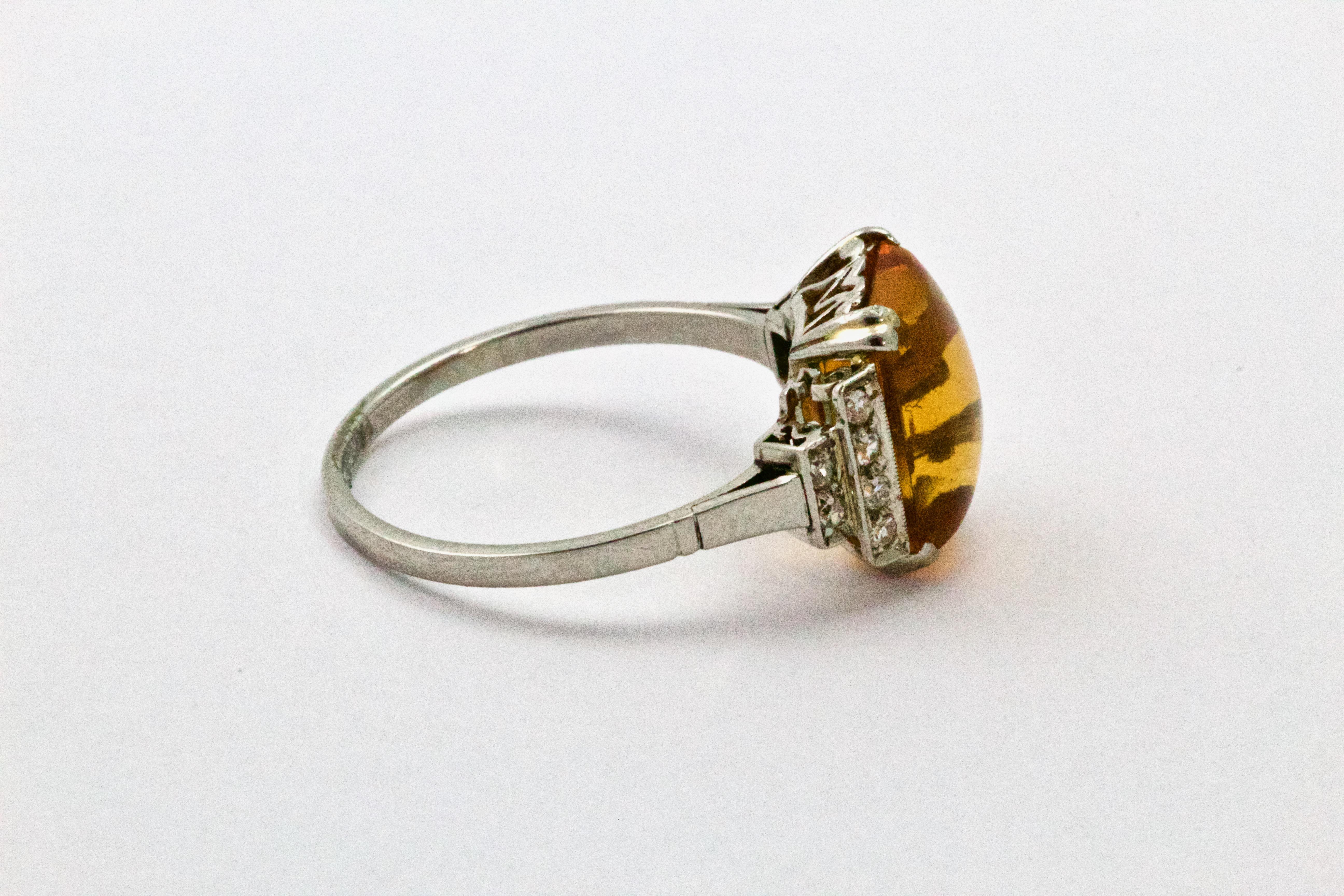 A Stunning example of an Art Deco cabochon Citrine ring, flanked with diamond stepped shoulders, modelled in platinum throughout with simple track embellishment to the band.

Ring Size: Q or 8 

Weight: 4.4 grams