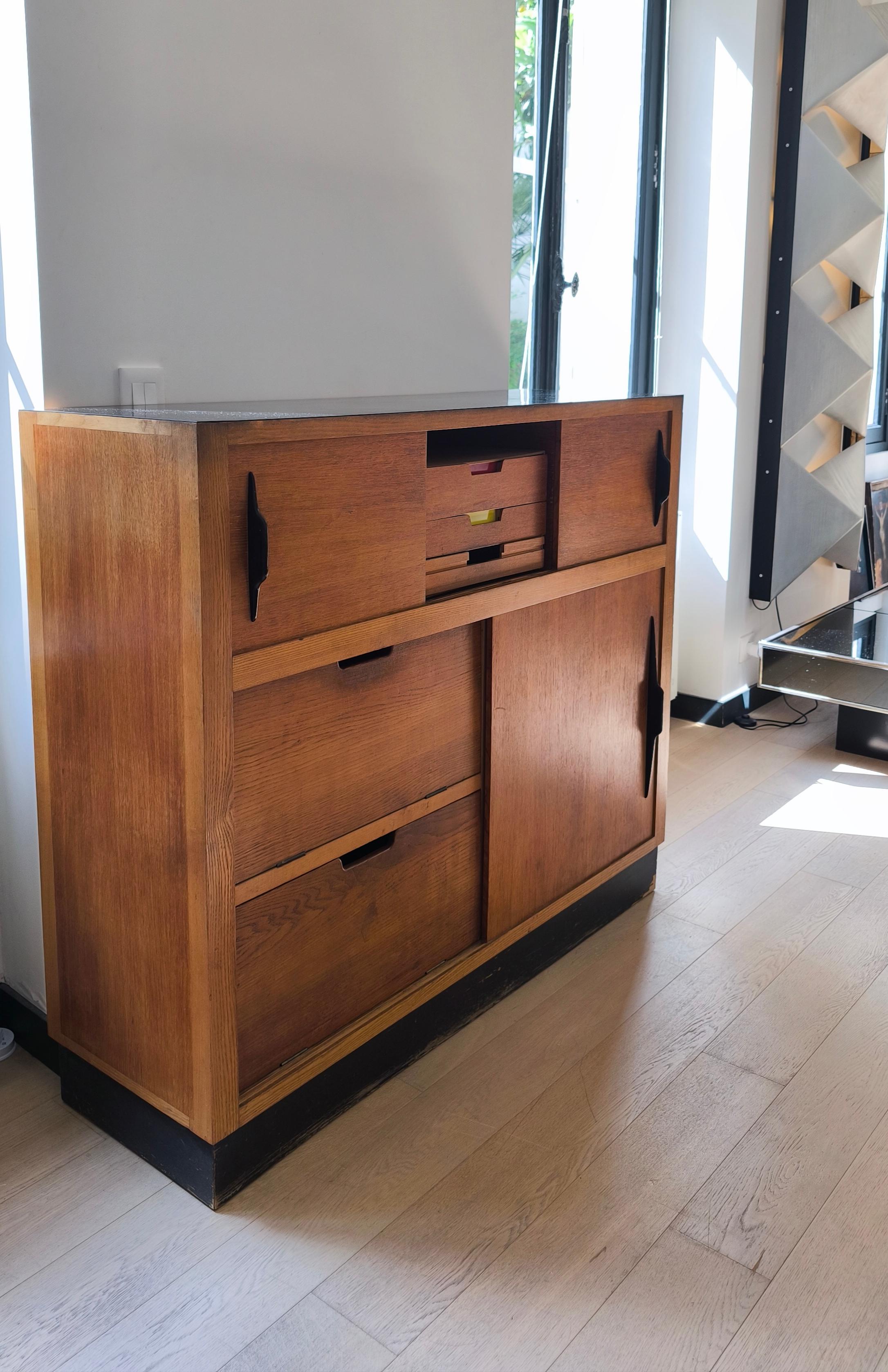 Built around the 1950s, this unique rectangular cabinet/sideboard is made entirely of wood with a top that appears to be black melamine and rests on a black wooden base.
.
It features three sliding doors on the front with black wooden wing-shaped