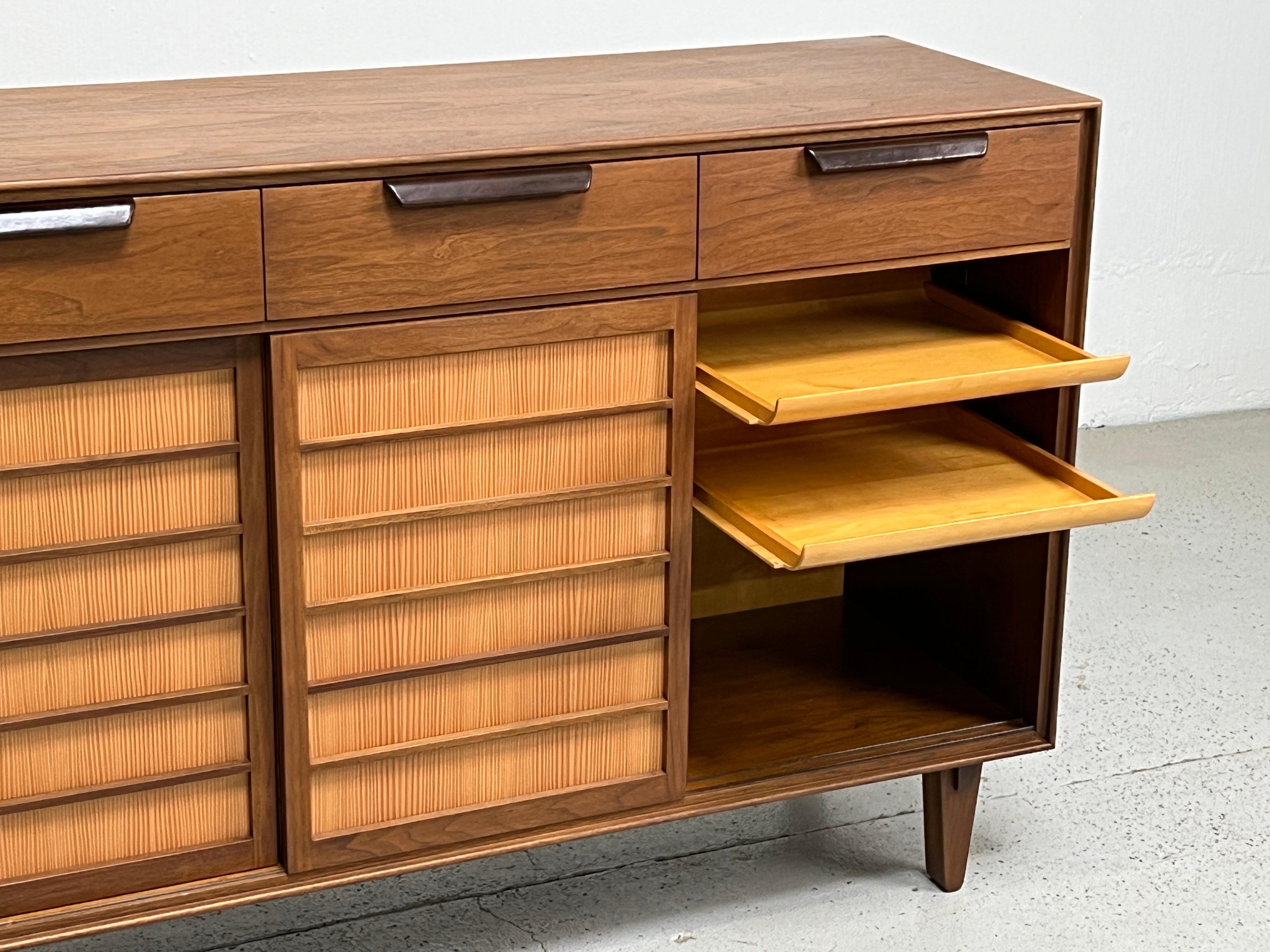 A walnut cabinet with leather wrapped handles and spruce sliding doors. Designed by Edward Wormley for Dunbar.
