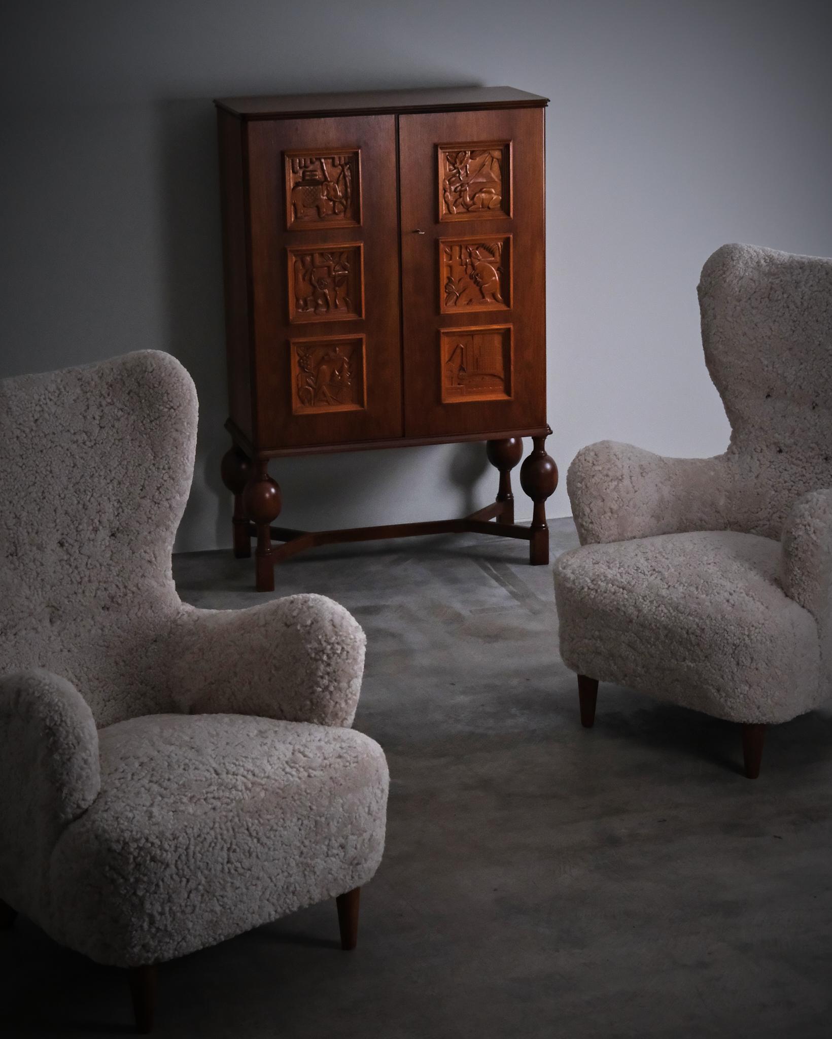 A cabinet designed by Eugen Höglund and produced by Bildhuggarverkstad Vetlanda in the 1940s. The two doors are richly adorned with hand-carved panels depicting stylised animal and nature motifs.

Made in walnut with finely carved detailing. The
