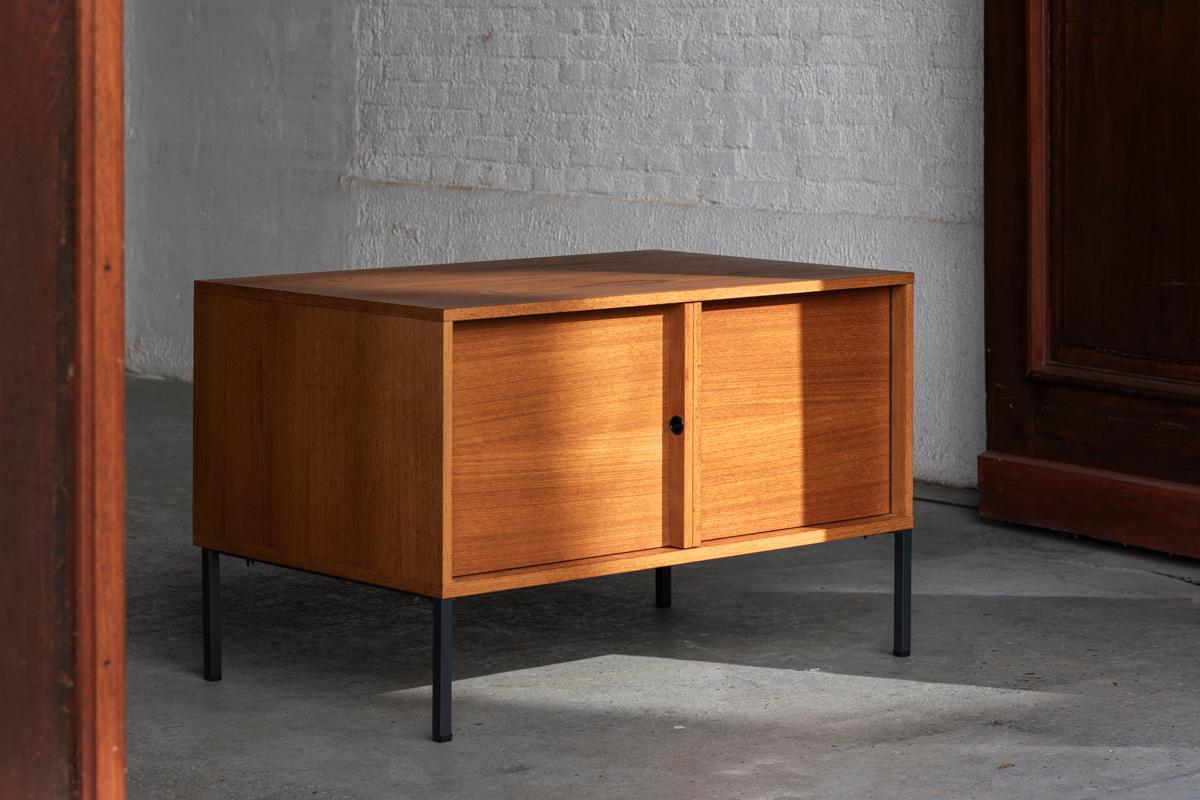Cabinet designed by Günter Renkel and produced by Rego in Germany around 1960. This minimalist cabinet features black lacquered steel legs and a teak veneer cabinet. Carries the makers label by Rego. In good condition as shown in the pictures. We