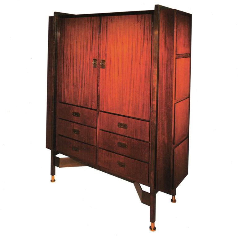 A mahogany and brass-mounted cabinet by Jacques Adnet. The pair of cupboard doors enclosing four adjustable shelves above six drawers, the sides with four hinged compartments.