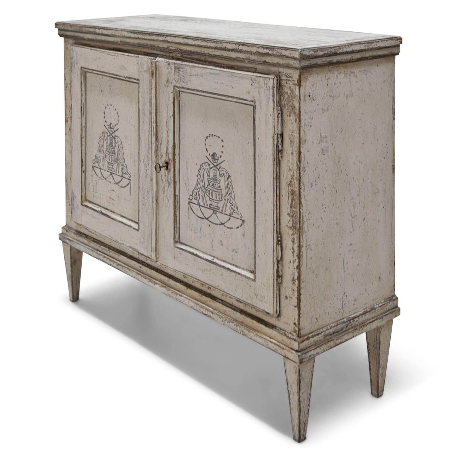 Hand-painted cabinet standing on tapered feet with two doors and profiled edges. The Gustavian-style crème-colored paint is new and has an aged patina. The fillings on the doors show designs of unicorns and amphora.
