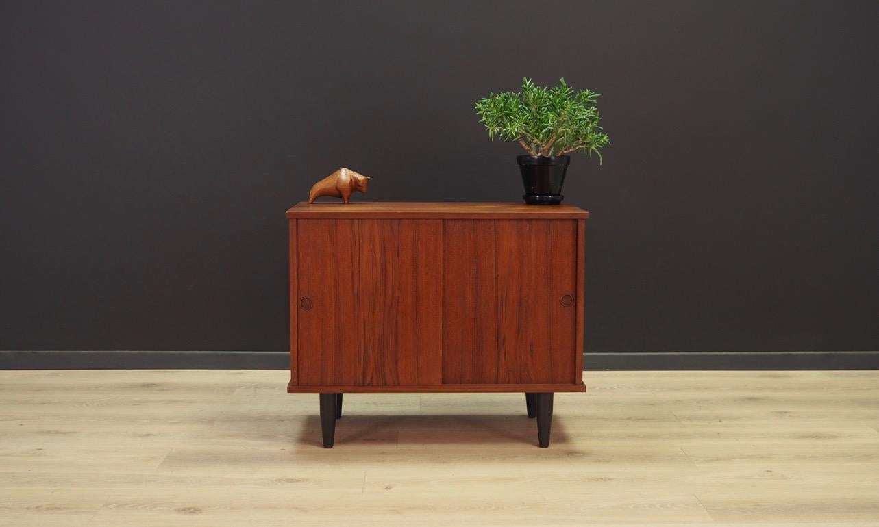 Classic cabinet from the 1960s-1970s, Danish design. Surface finished with teak veneer. Item has a shelf behind the sliding doors. Preserved in good condition (minor scratches), directly for use.

Dimensions: height 60.5 cm width 75 cm depth 38 cm