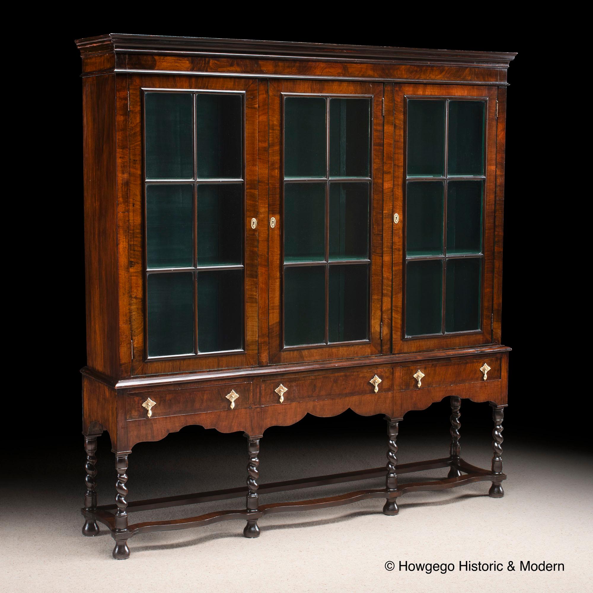 Unusual, antiquarian, glazed, display cabinet or bookcase on stand in the Baroque-Style most likely made for a formal interior
Beautifully made walnut cabinet piece using finely figured, crossbanded and engraved brass handles
The shaped stand has