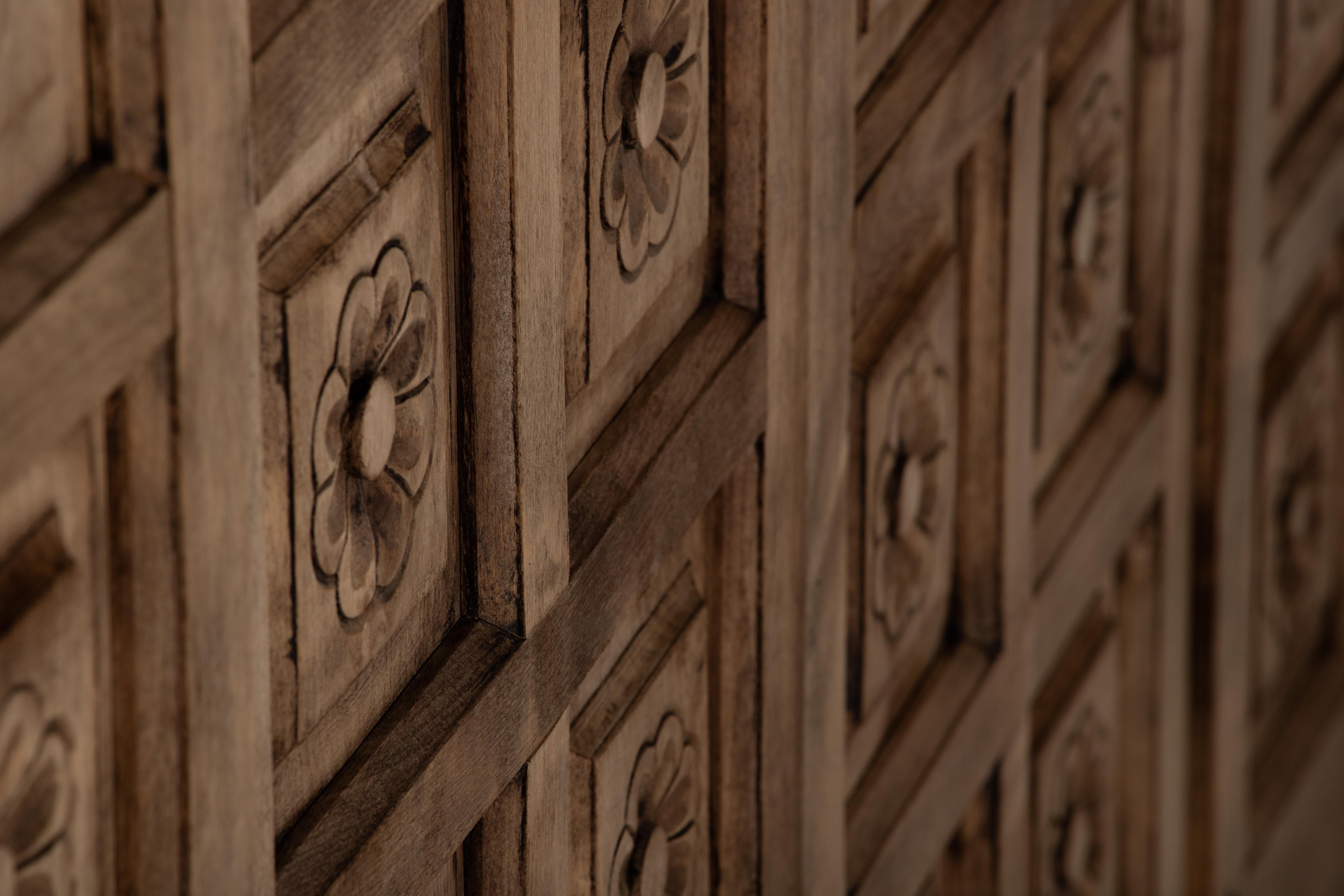 A façade of rhythmic florals emerges from a field of quiet geometry—each rosette delicately recessed in its own square niche, like votive offerings set into a chapel wall. This cabinet presents not as furniture but as a ceremonial artifact: