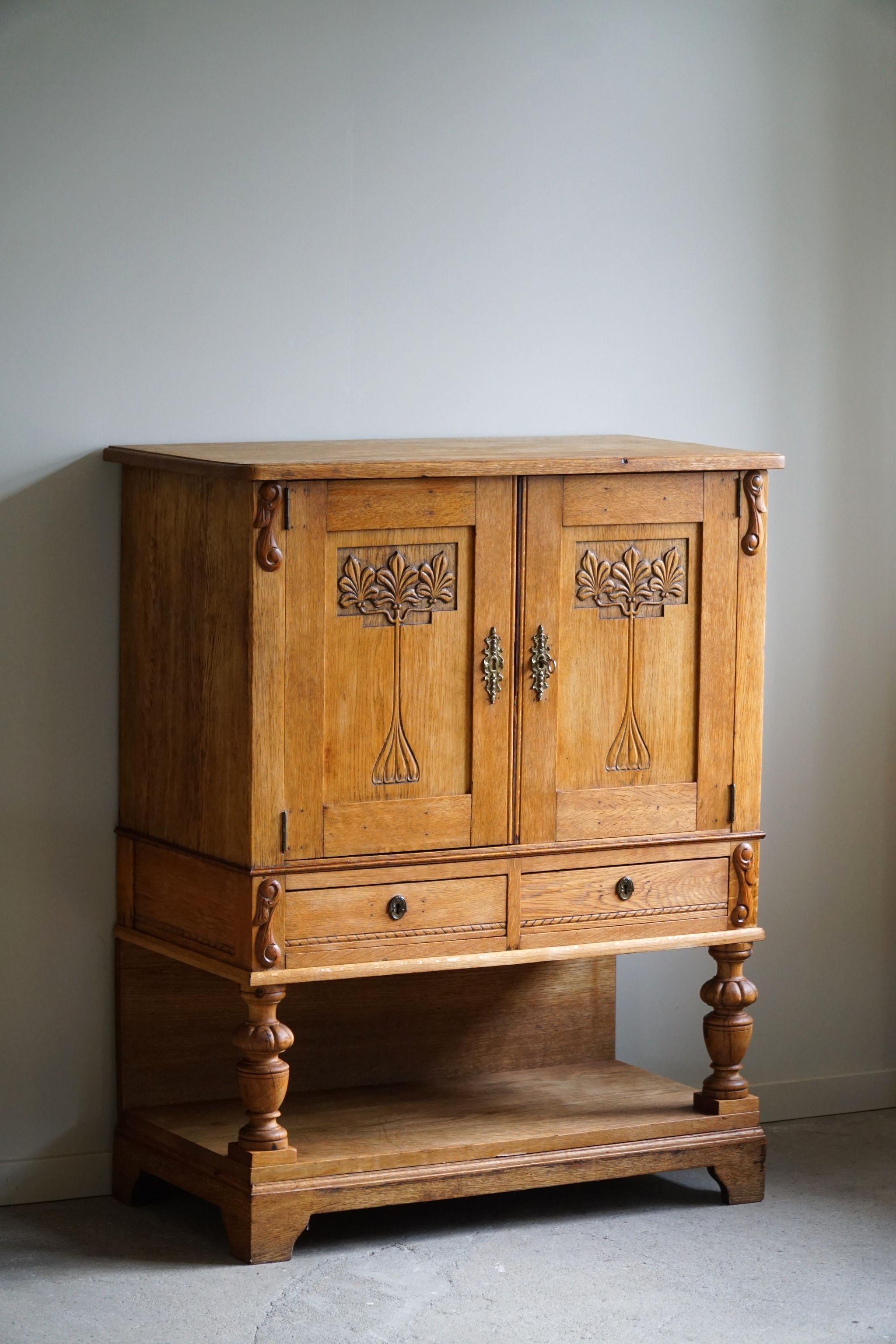 An exquisite handcrafted cabinet in solid oak - a perfect storage furniture for the living room with space for your art and books. Crafted by a skilled Danish cabinetmaker in the 1920s. Constructed from oak wood, known for its durability and