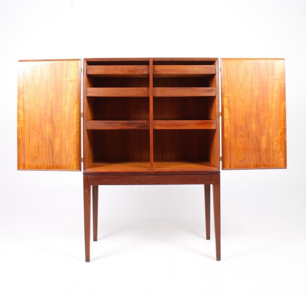 Tall cabinet in teak with brass hardware designed and made in Denmark in the 1950s. Works well as a bar cabinet .The cabinet is in great quality and all original condition.