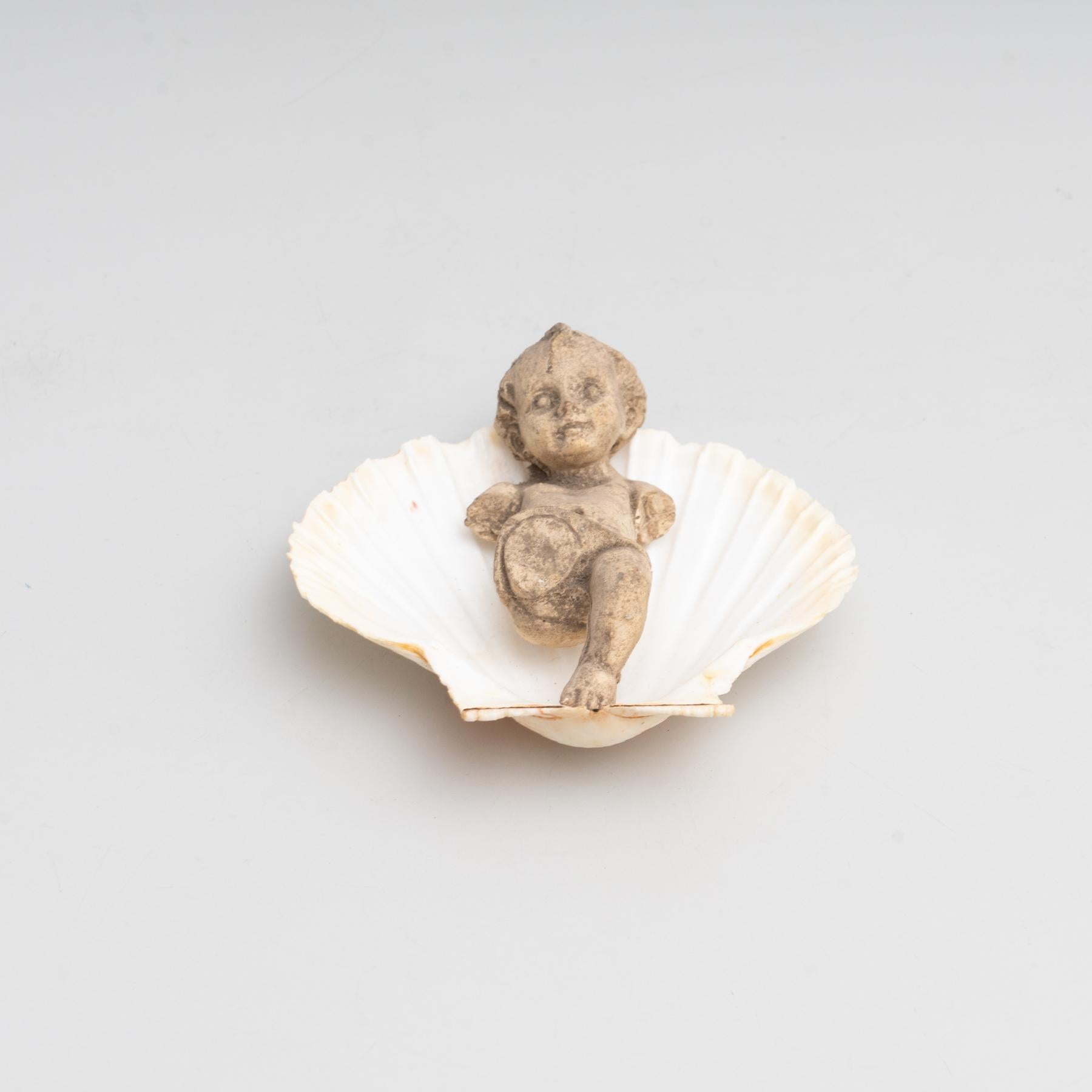 Cabinet of curiosities of plaster baby Jesus on a shell stand.

Made in traditional Catalan atelier in Olot, Spain, circa 1950.

Olot has a long tradition in the production of sculptures and religious imagery. The art and industry of religious