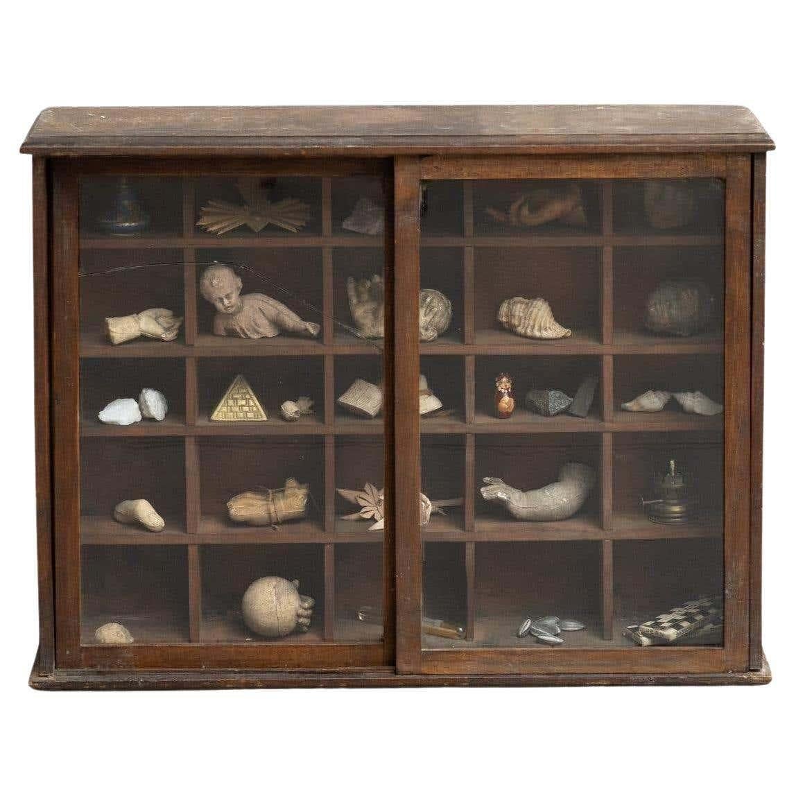 Gabinete de curiosidades de figuras de escayola, piezas y coleccionables en vitrina de madera y cristal.

En su estado original, con pequeños desgastes propios de la edad y el uso, conserva una hermosa pátina.

El cristal tiene algunas grietas como