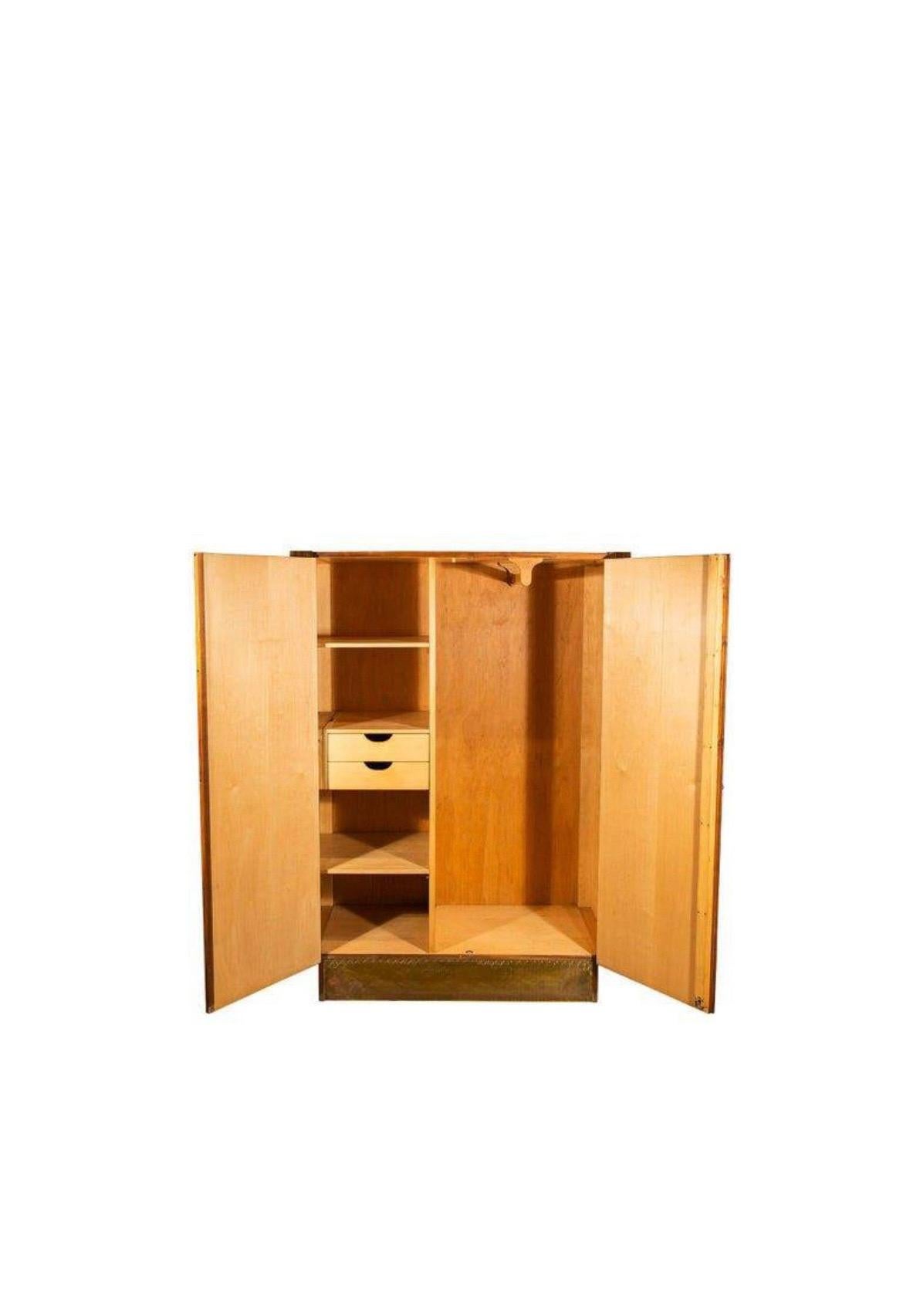 A stunning small Cabinet - Wardrobe in polished teak wood, With rounded Brass details. The piece is beautifully made, and has a distinkt Art Deco reference. The cabinet has two compartments, one with drawers and shelves and one with hangers.

The