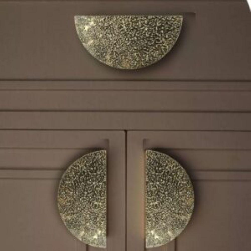 This semi-round cabinet pull measures 12 cm in diameter and features a clean, geometric silhouette with a strong visual presence.
Its design relies on a full, unadorned surface animated by a lightly hammered texture. The regular outline contrasts