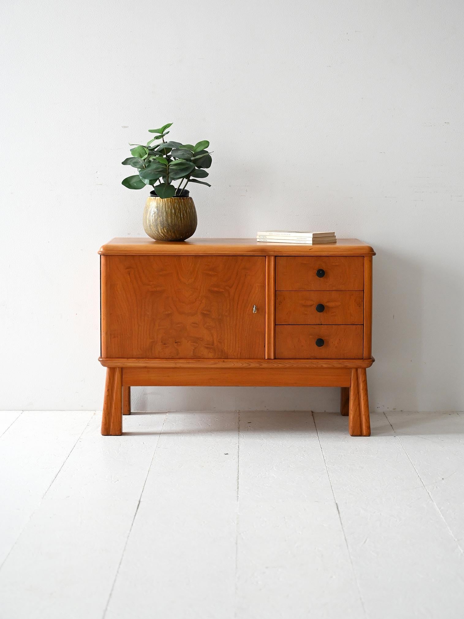 1930s elm cabinet with sturdy lines and carved legs, equipped with storage compartment and three drawers.

Scandinavian Deco cabinet made of elm in the 1930s. The compact structure features sculpted legs that widen downward, raised profiles, and