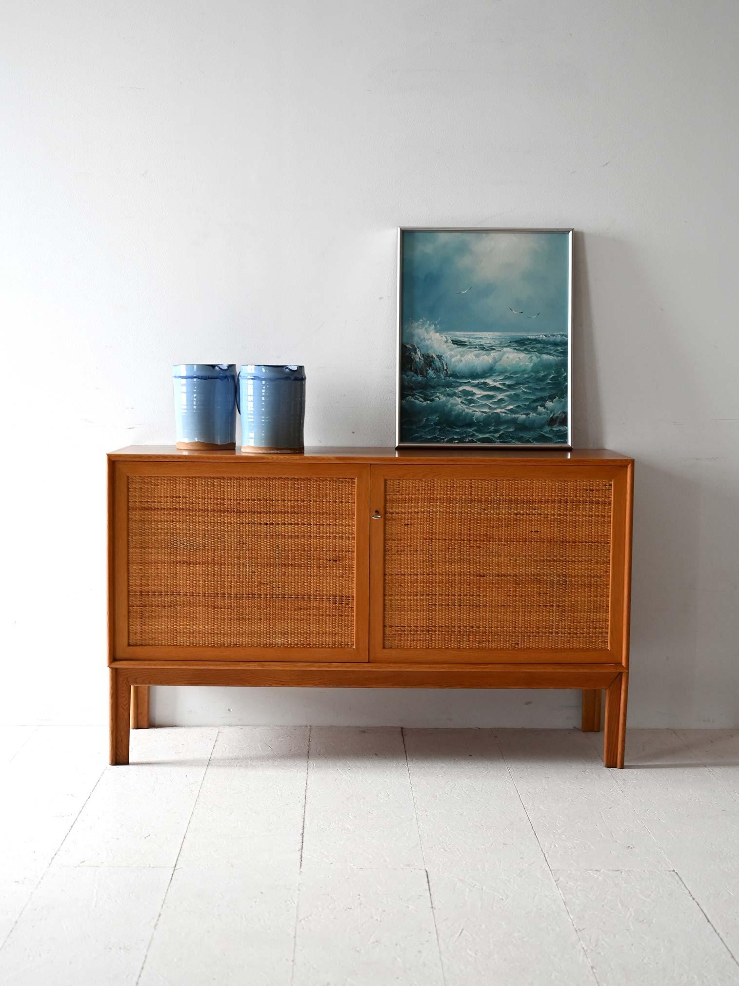 Swedish cabinet with original branding, oak frame, woven rattan hinged doors and interior shelves.

Scandinavian vintage light oak cabinet with hinged doors covered in woven rattan. Made in Sweden and designed by Alf Svensson, it features a solid