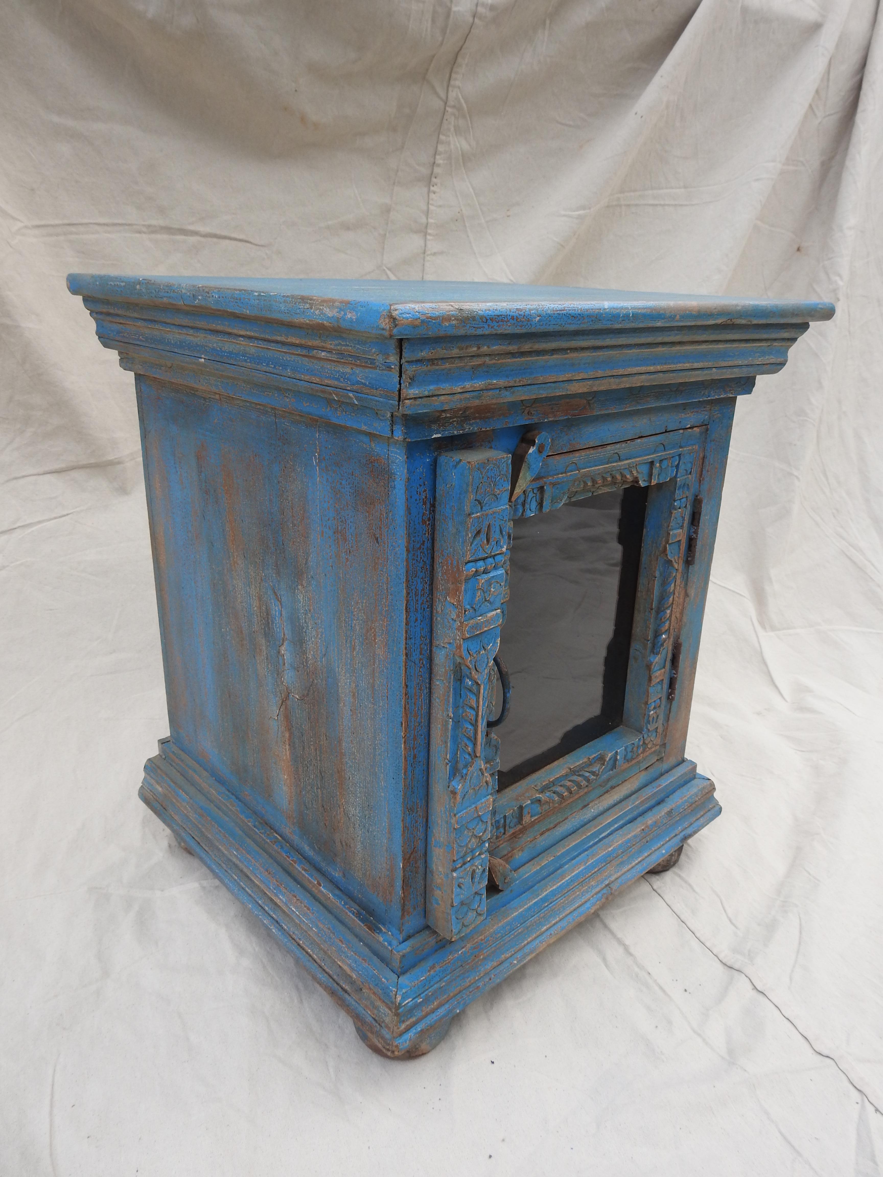 Hand painted turquoise table with glass door. Perfect for a side cabinet or end table. Having some relief carving to the door. Sits on 4 turned bun feet.