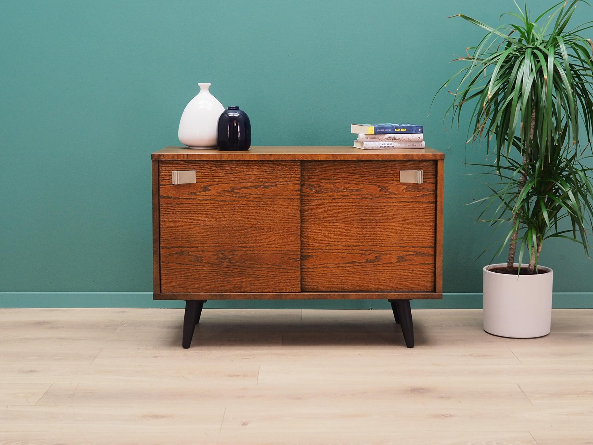 Stunning cabinet from the 1960s-1970s. Danish design, Minimalist form. The furniture is covered with oak veneer. The cabinet has two doors with metal handles, inside there is one shelf. Preserved in good condition (small upholstery and scratches,
