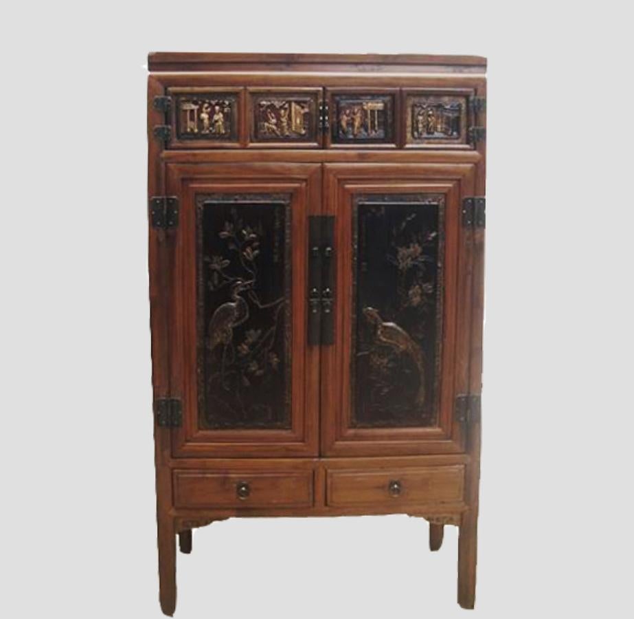This cabinet has a beautifully carved crane and phoenix on each door panel with eight figures carved on the top of the narrow panel doors. Painted with black lacquer and gilded, this cabinet will draw attention in any room. It has two shelves, two