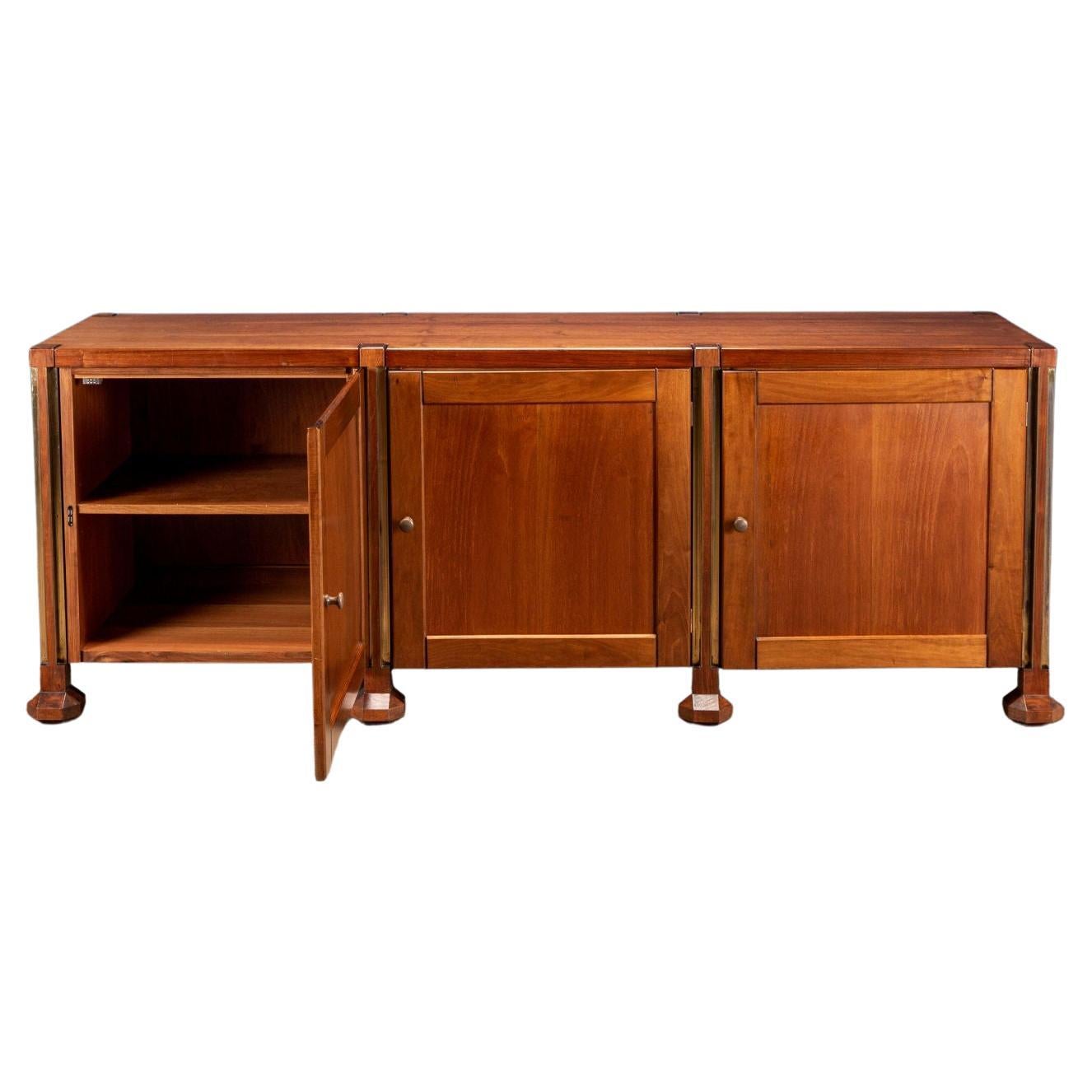 Elegant 60's sideboard of Italian manufacture. The cabinet is made up of uprights with brass profiles ending with polyhedral feet and storage compartments with hinged doors. Walnut veneer.