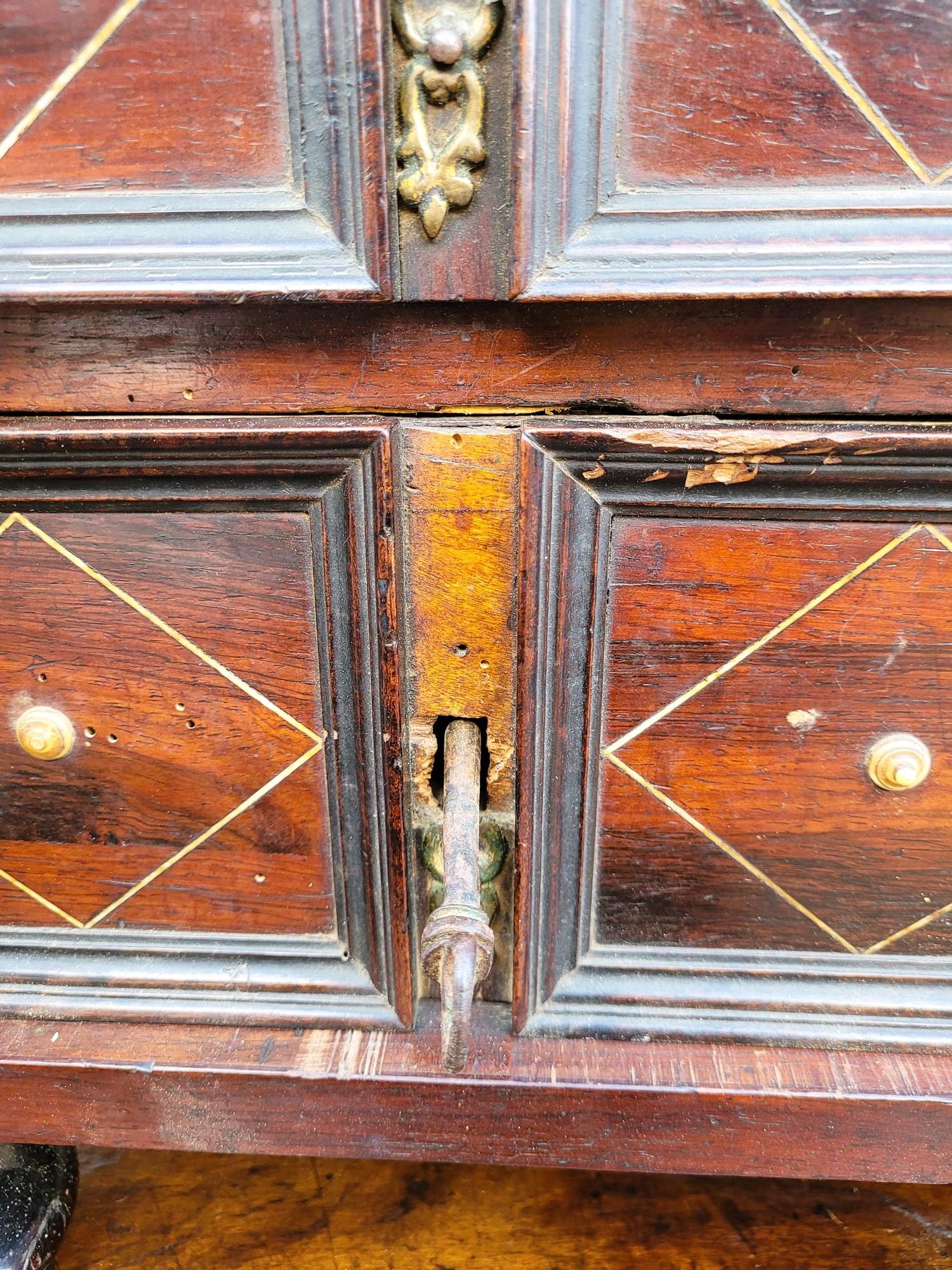 Grande mobile in intarsio, aperto sul davanti con 12 cassetti decorati con rombi e bottoncini in osso e poggiante su 4 piedi a forma di formaggio; i lati sono decorati con rosette.

Armadietto del XVII secolo: impiallacciatura mancante, bottoni in