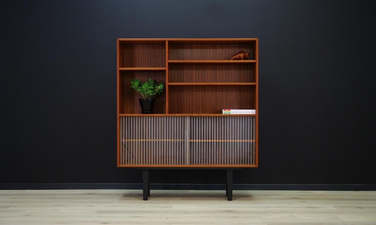 Cabinet/bookcase from the 1960s-1970s - minimalistic form, Danish design. Finished with teak veneer, item also has a sliding decorative glass. Preserved in good condition (minimal dings and scratches) - directly for use.

Dimensions: height 139