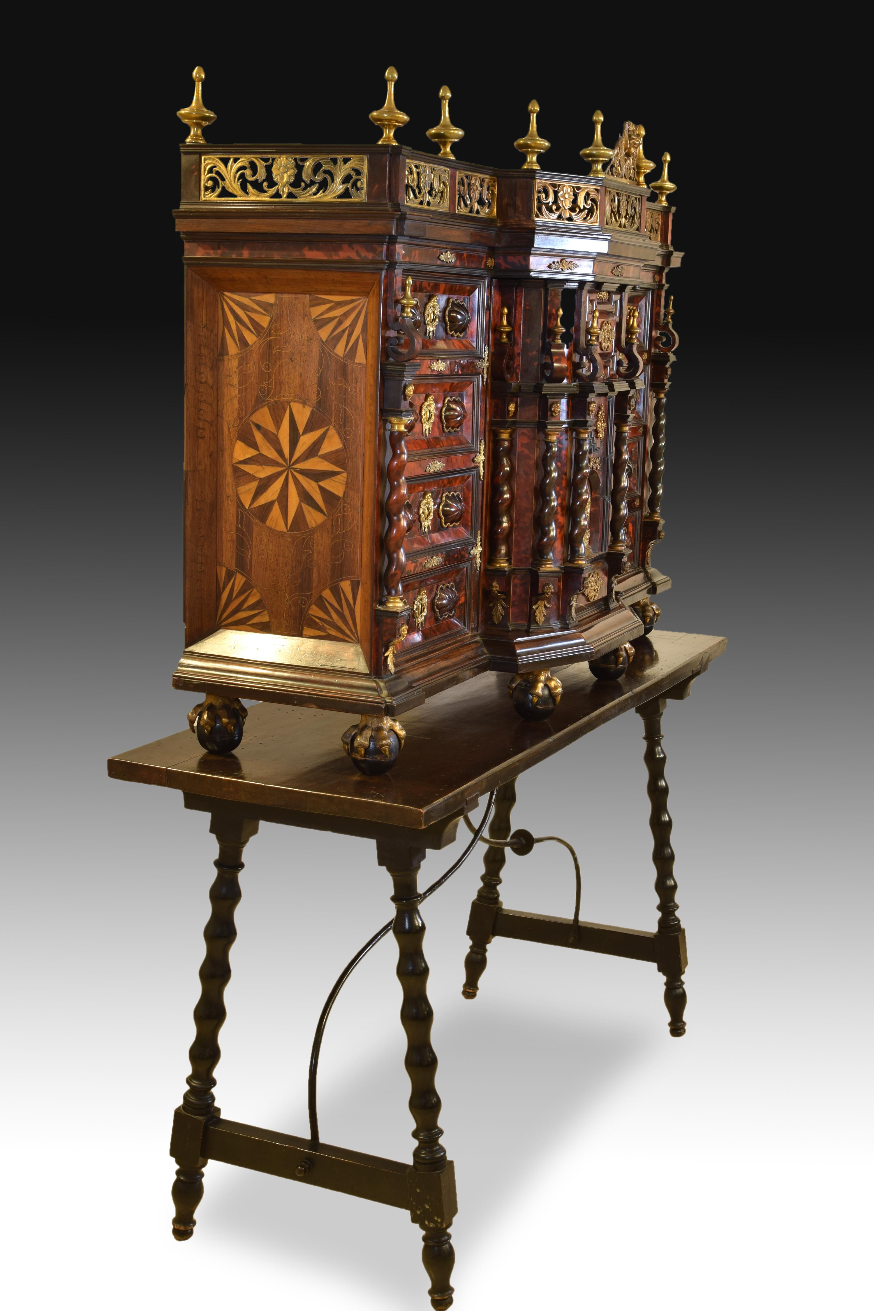 Bargueño. Tortoise, bronze, wood, iron. Italy, 17th century; rear table.
Uncovered sample desk made of wood and finished in tortoiseshell that has a division into three areas at the front. The sides have four drawers each (each with two veined