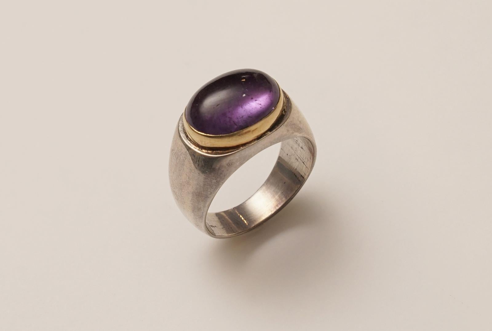 An elegant large cabochon amethyst set in 18K gold (weighted, not plated), and the band is in sterling silver.  Ring size is 8.