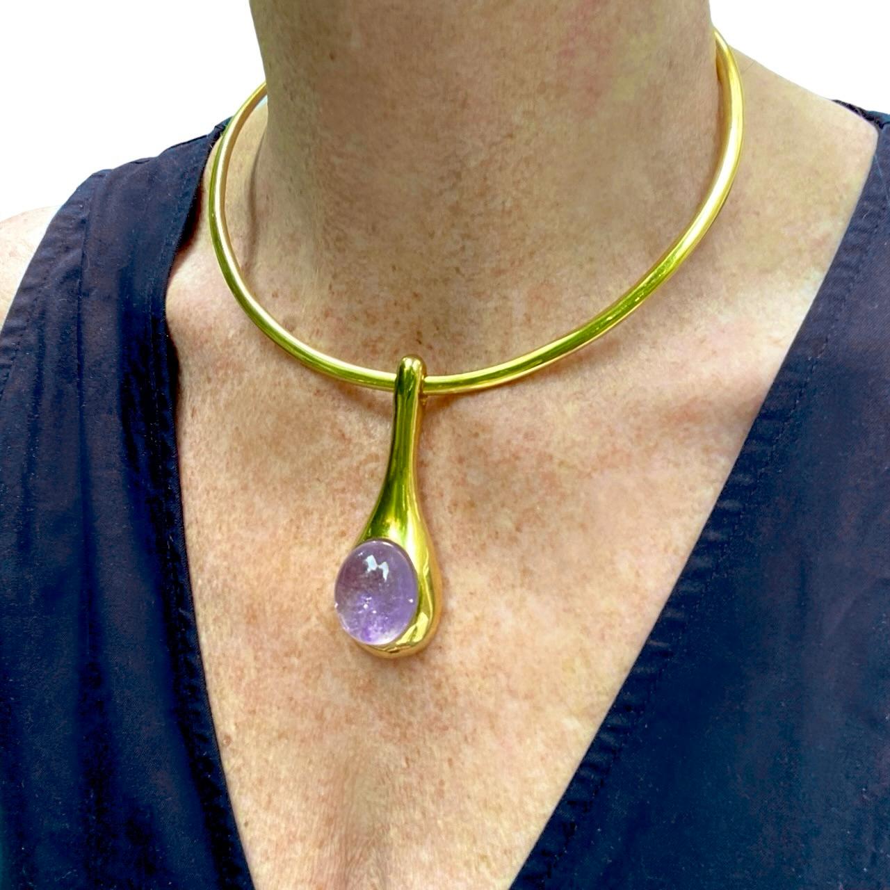 Ce pendentif en forme de goutte, merveilleusement élégant et sinueux, est serti d'un grand cabochon ovale d'améthyste pâle. Cette pièce est extrêmement polyvalente et peut être portée sur un collier pour des soirées ou des occasions formelles, ou