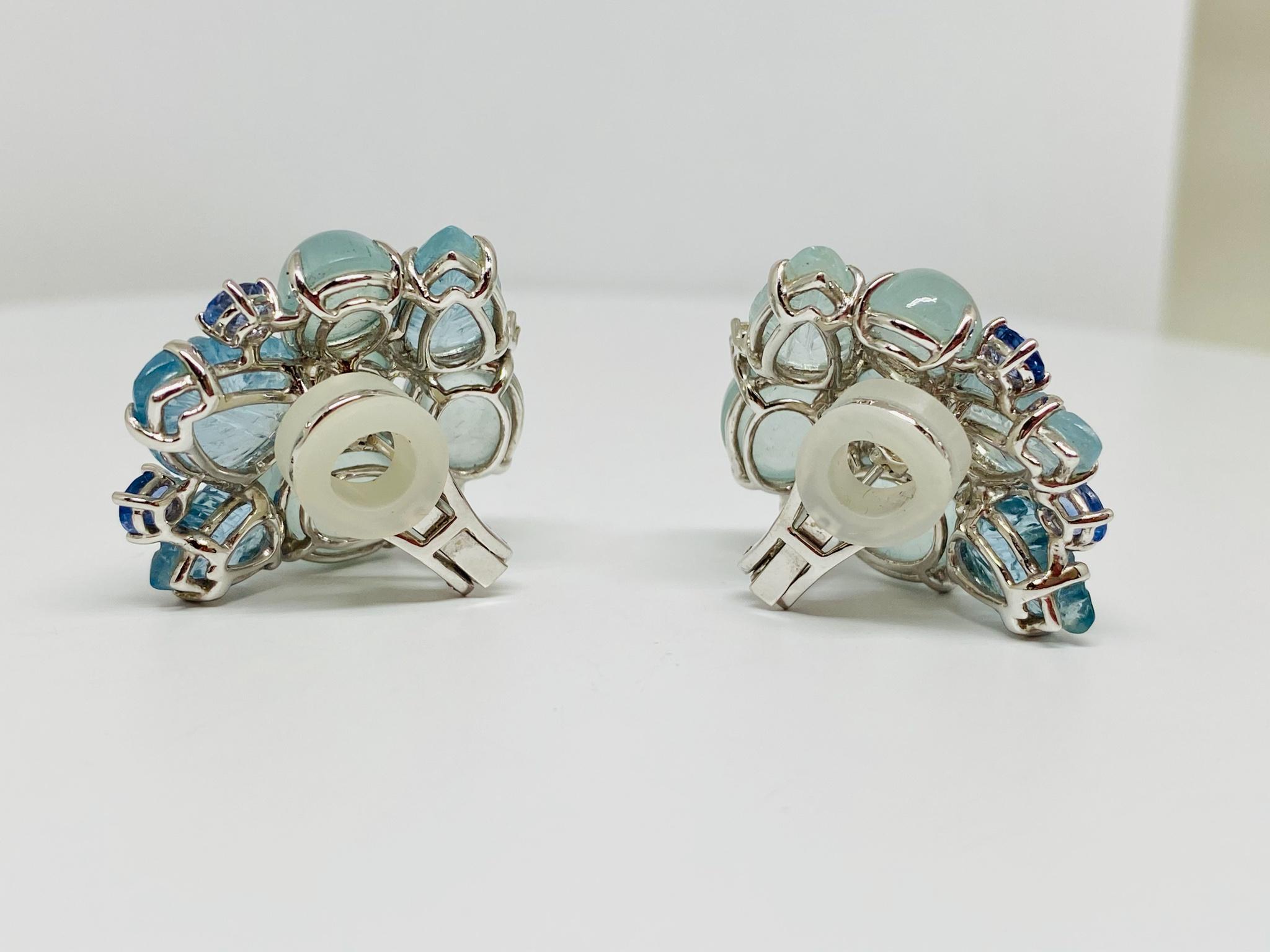 Superbly designed beaded clip-on earrings in 18KT white gold featuring an array of oval cut and leaf shaped cabochon aquamarines with a total weight of 46.15 carats all accented by round and oval cut blue and white sapphires weighing a total of 
