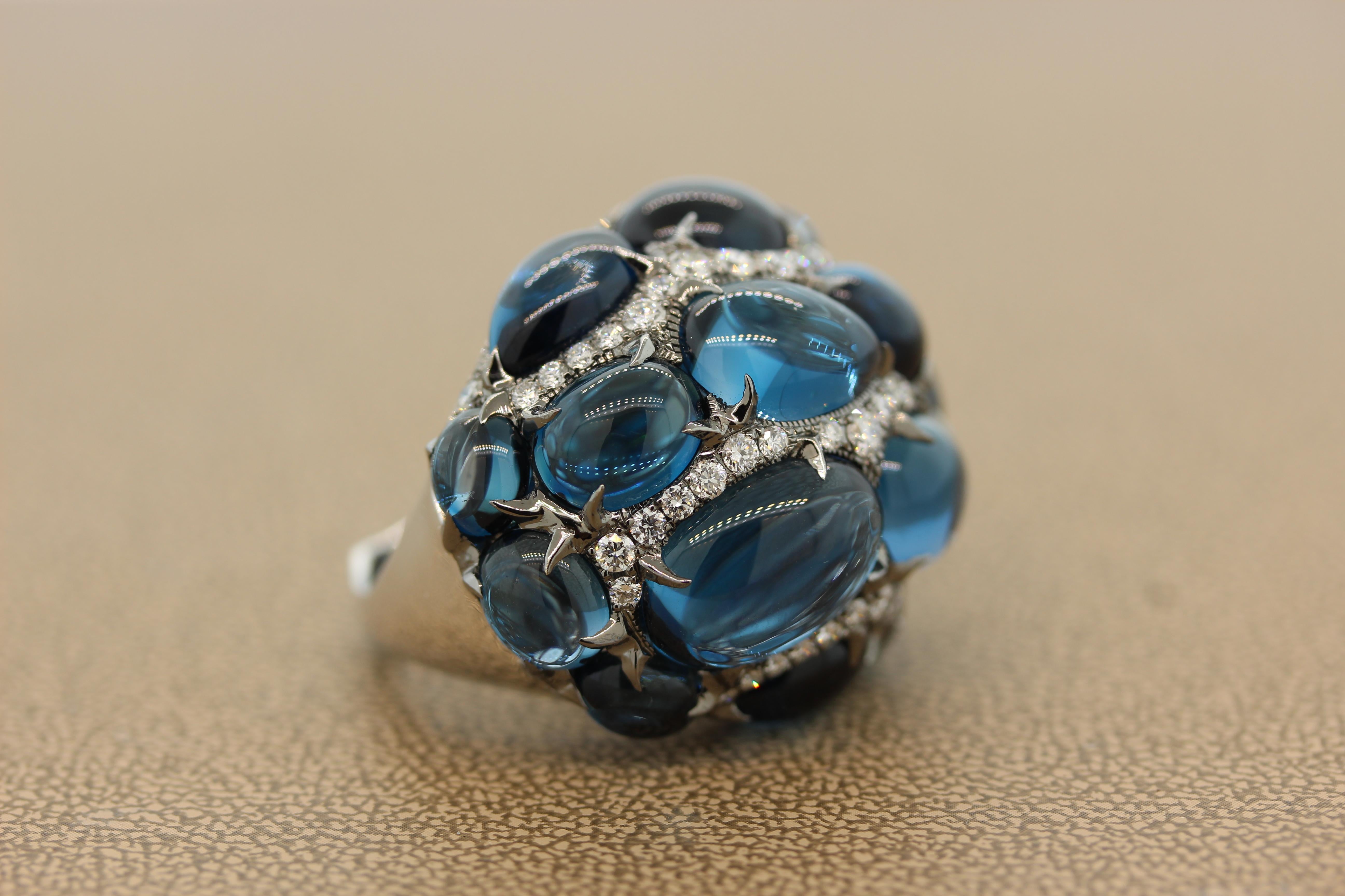 An opulent cocktail ring featuring 52.48 carats of topaz with a rich deep blue color. The cabochon oval, pear and round shaped topaz are accented by 1.70 carats of sparkling round cut diamonds. This dome shape ring is made of 18K white gold and one