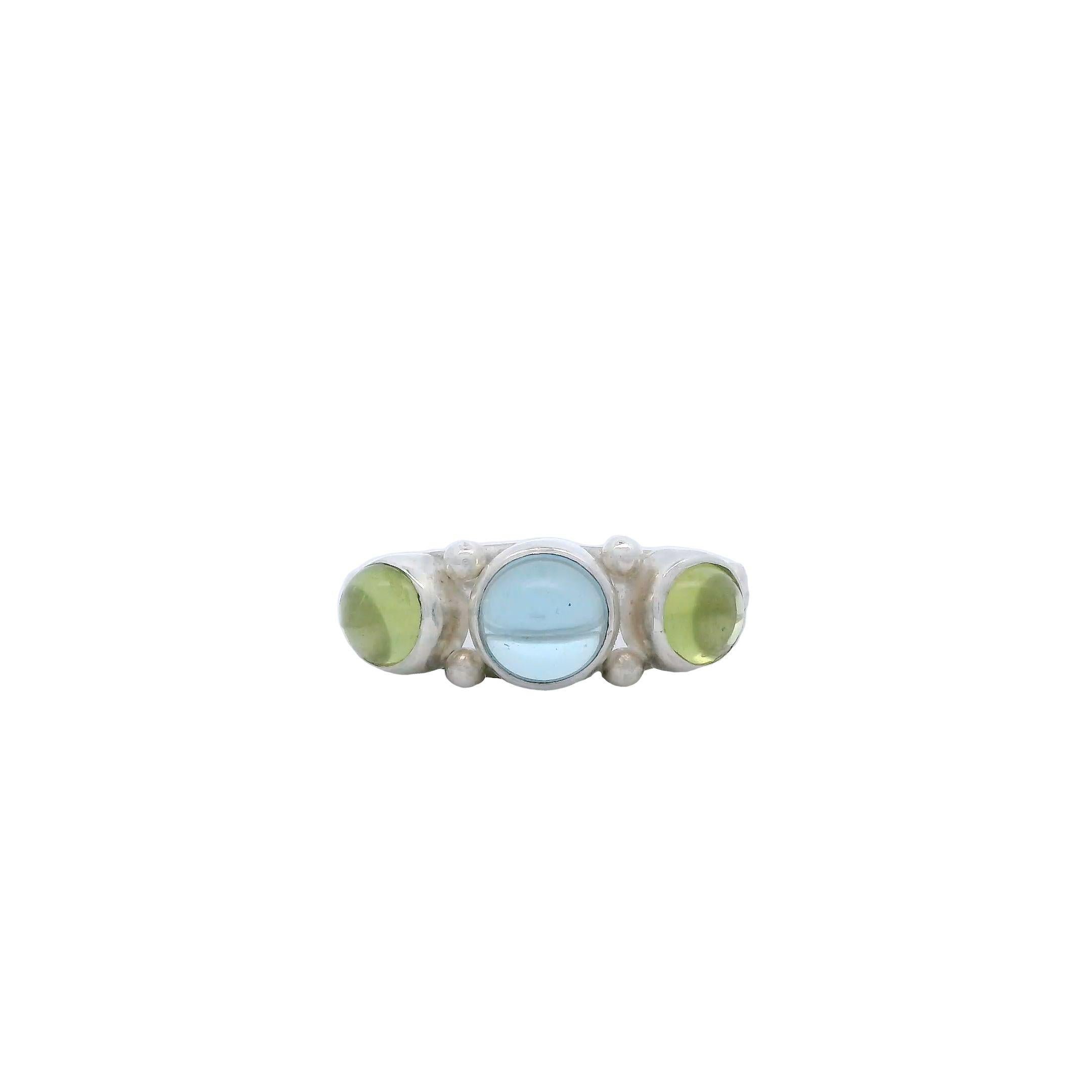 Lassen Sie sich von diesem bezaubernden Ring mit Cabochon aus blauem Topas und Peridot verzaubern, der von Lynn Kathyrn Miller, einer renommierten Kunsthandwerkerin und Inhaberin von Lynn K Designs, handgefertigt wurde. Die beruhigenden Farbtöne des