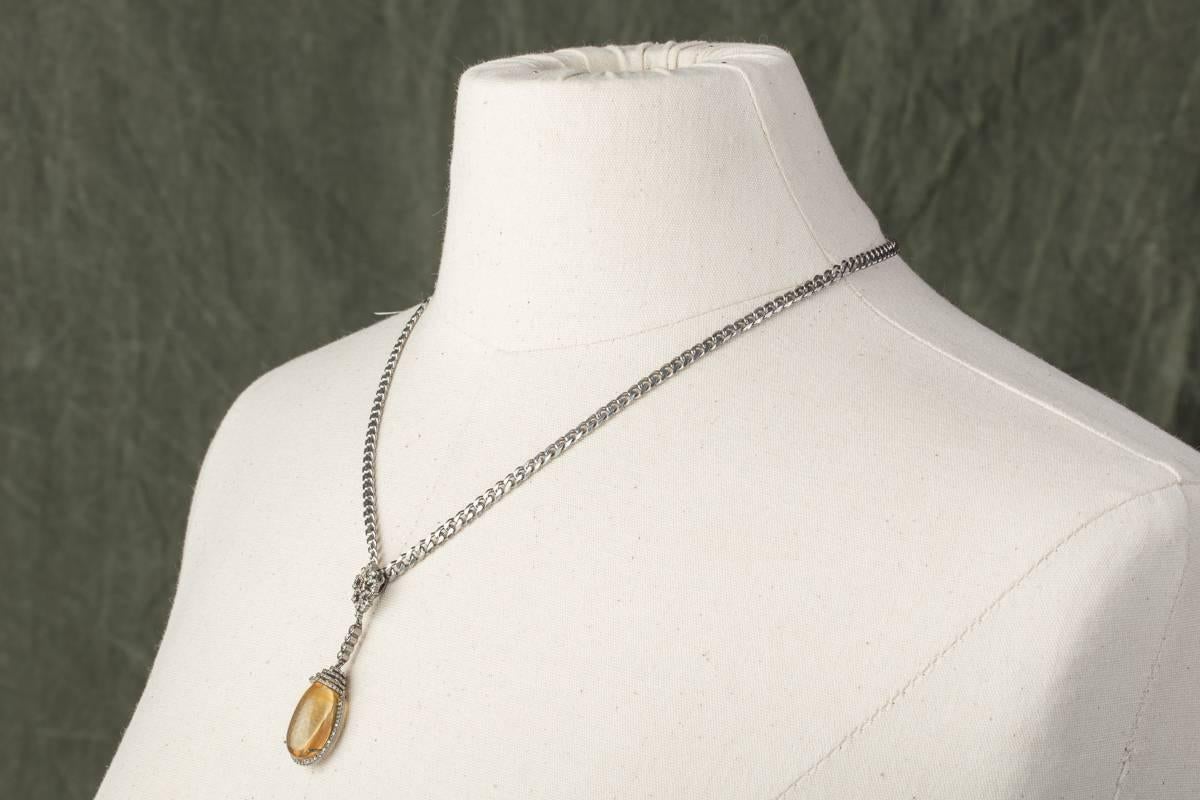 A lovely, large cabochon citrine bordered and topped with pave`-set diamonds with an intricate diamond bail.  Hangs from a sterling silver figaro chain.  The citrine is 23.80 carats and the diamonds weigh 1.3 carats.  Chain can be optional.  Just