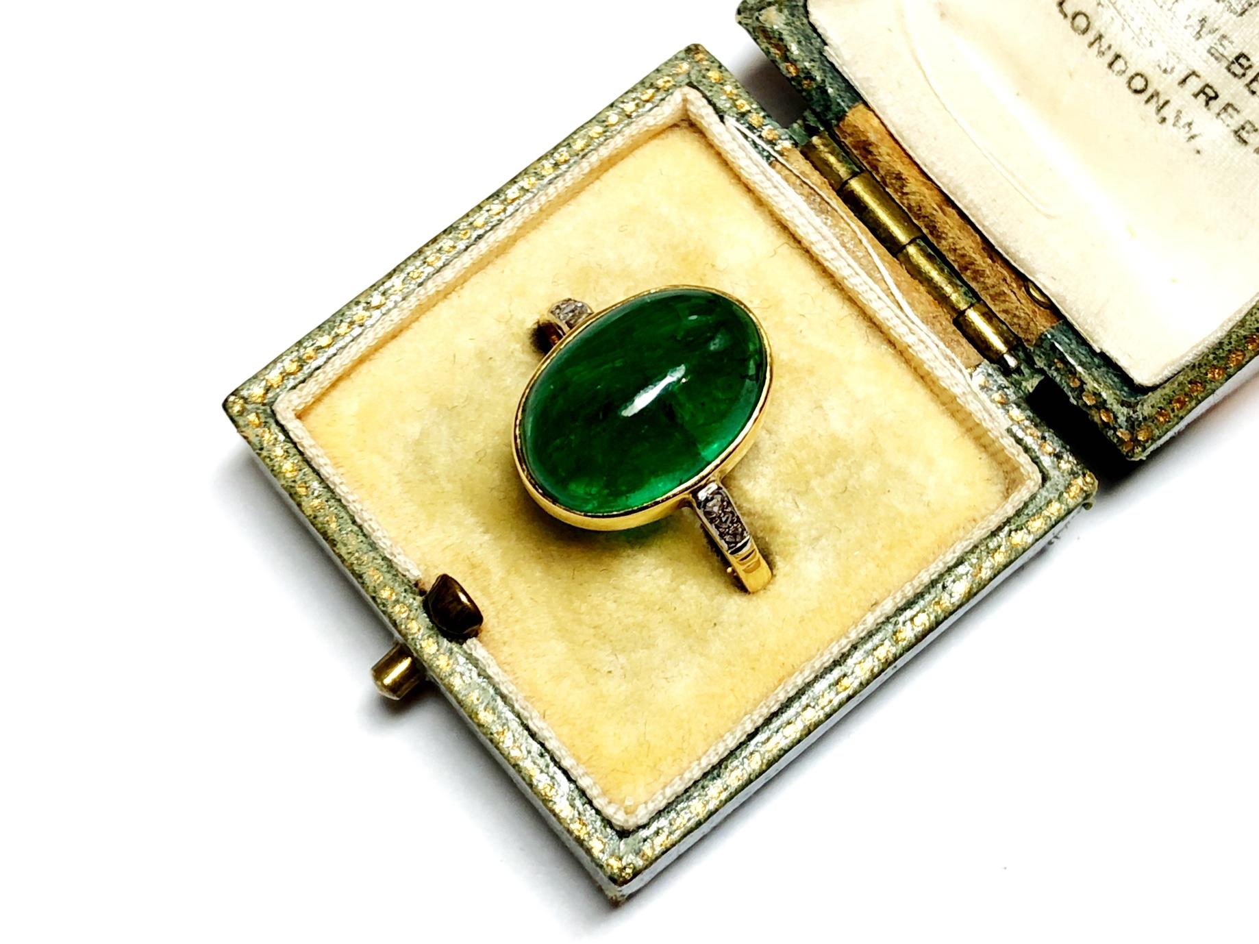 An Art Deco period emerald ring, with a cabochon-cut emerald, in a rub over setting, mounted in 18ct yellow gold, with three diamonds set in each shoulder, in white gold settings, with an estimated emerald weight of 2.90ct. English, circa 1920.