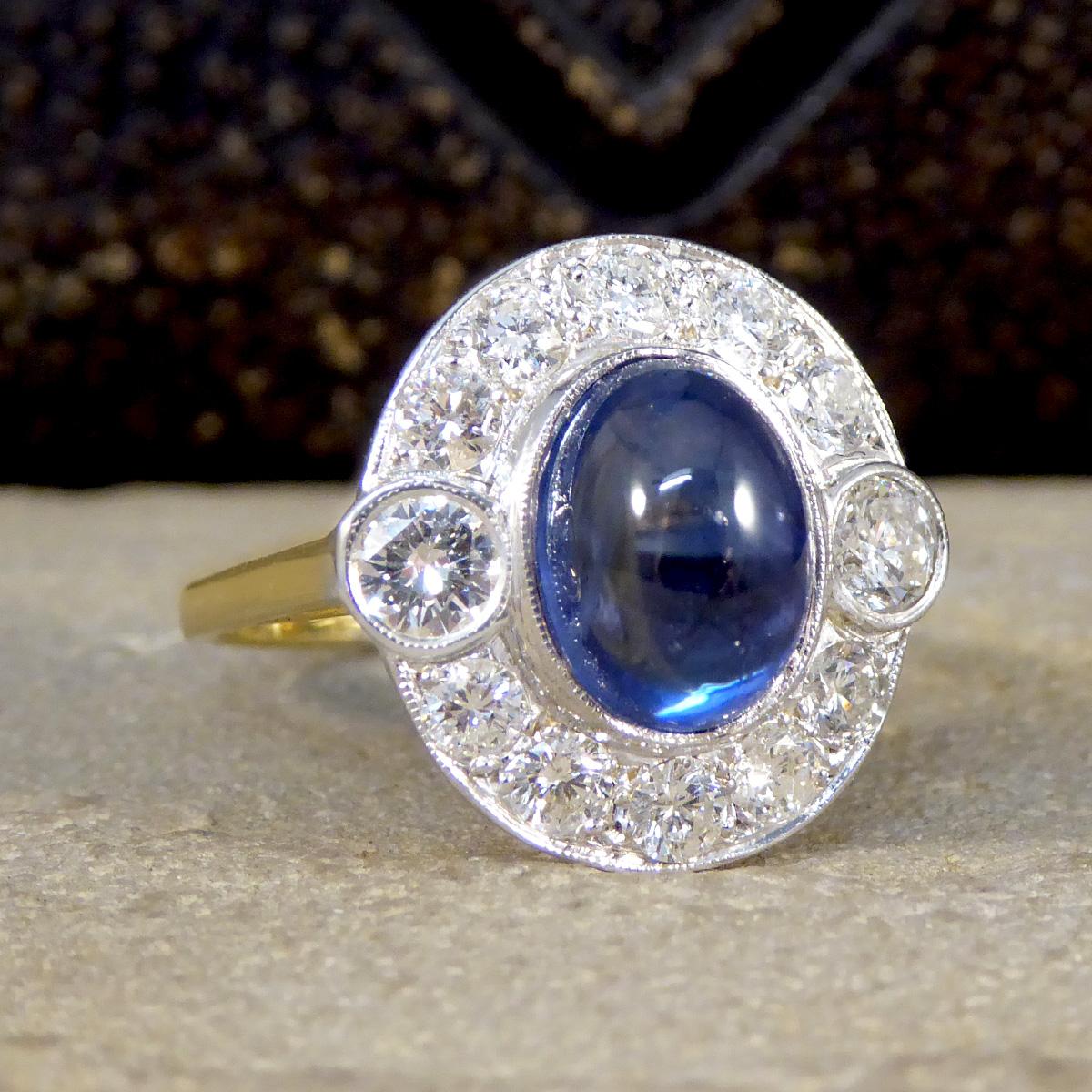 This beautiful ring features an alluring blue cabochon cut Sapphire weighing 5.00ct held securely into place in a rub over bezel 18ct white gold setting. The Sapphire is surrounded by 12 brilliant cut Diamonds weighing 1.16ct in total, with two of