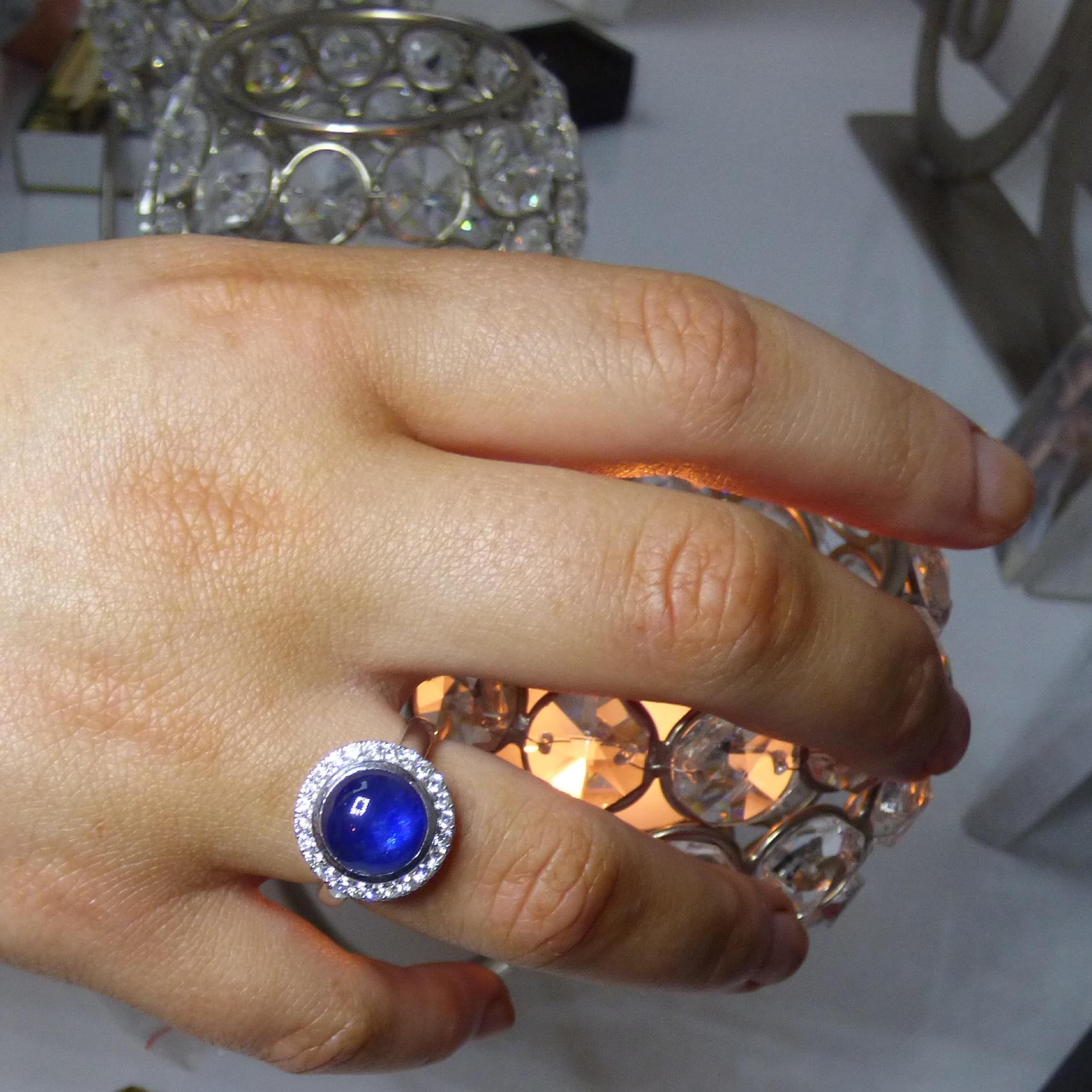 A colourful Cabochon Sapphire 9mm round (6.67ct.) is surrounded by 24 Diamonds (.43ct.). The ring is handmade in 14K white gold.  The ring is hallmarked by the Dublin Assay Office.
As noted in the photos, this cabochon Sapphire stands out with
