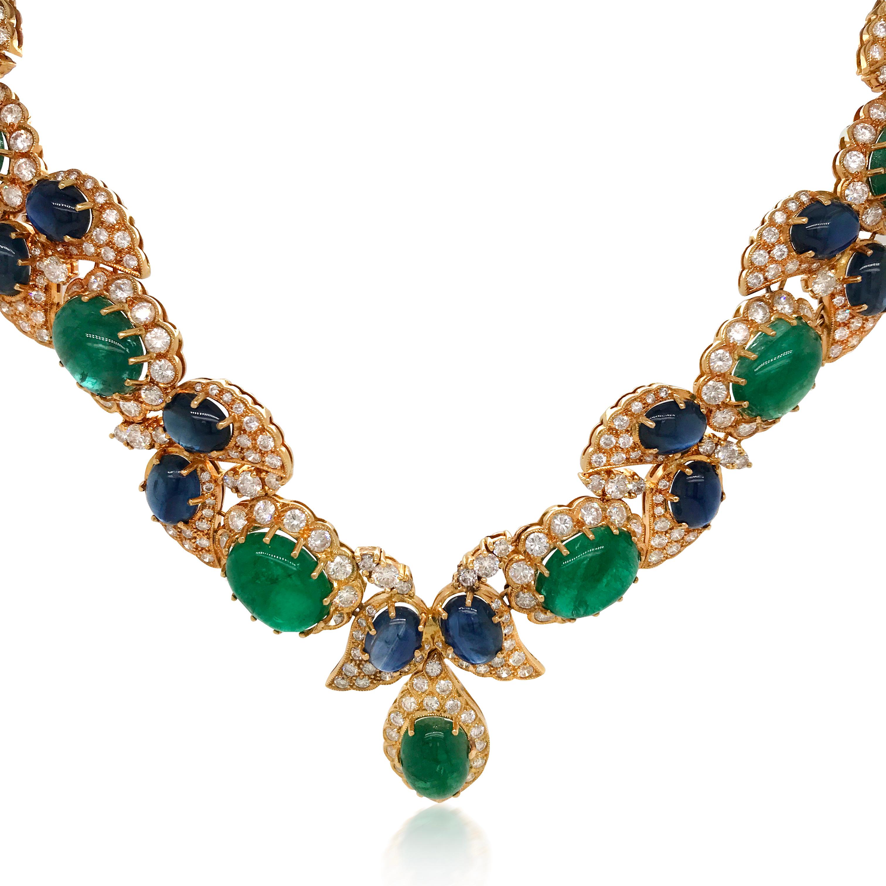 This extravagant and glamorous emerald, blue sapphire and diamond necklace is finely crafted in solid 18K yellow gold, decorated with 15  genuine cabochon-cut emeralds in the center with diamonds halo, further enhanced by 21 wing-motif profiles each