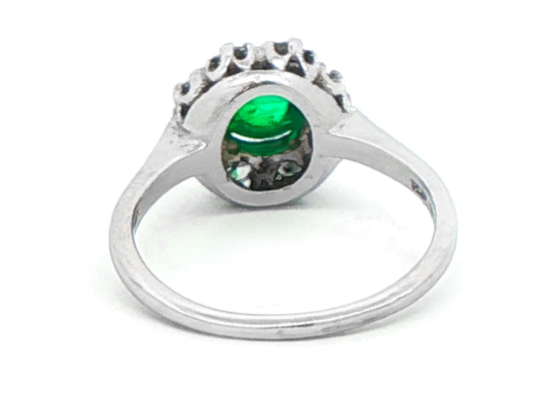 Platinum Emerald and Diamond Cluster Ring, featuring a center round cabochon emerald weighing 1.00 carat, surrounded by 8 round brilliant diamonds totaling 0.35 carats.  size  7 ½  circa 1960s