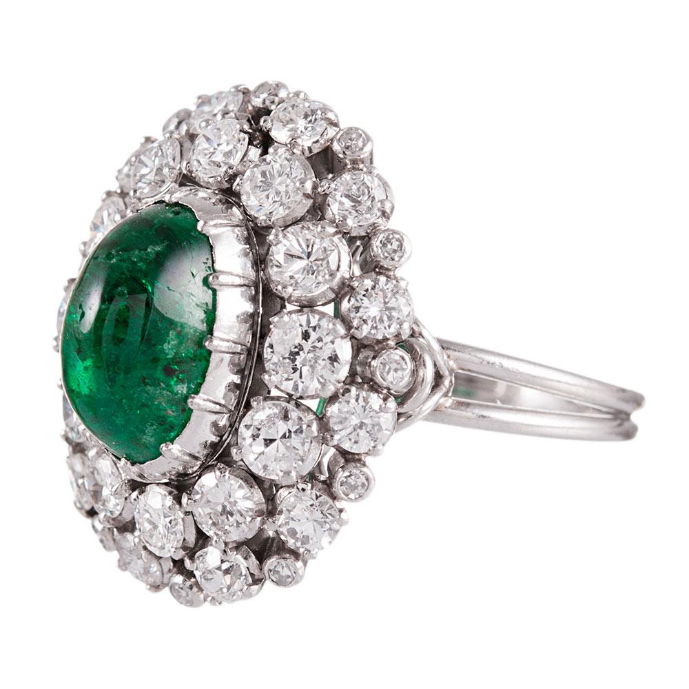 A double row of cluster diamonds dance around a cabochon emerald. The ring is made of 18k white gold and set with a 3.00 carat emerald and 4.00 carats of brilliant white diamonds. Size 8.25 can be resized on request.