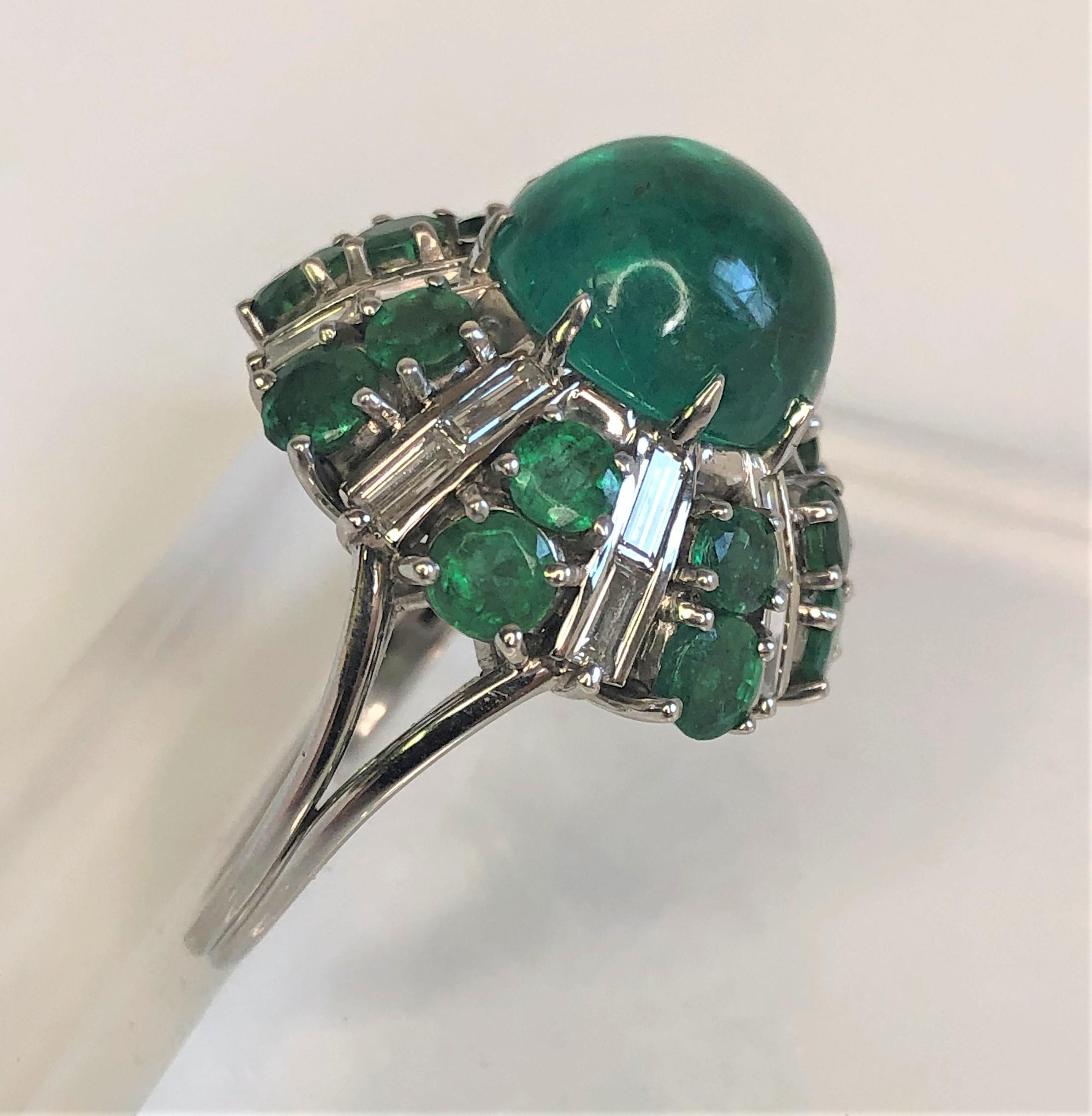 This vintage style ring sparkles from across the room!  
Platinum mounting with 17 total emeralds and 16 diamonds.
     Approximately 14 carats of emeralds (total weight).
     Approximately 1.60 total diamond weight.
Center cabochon emerald is