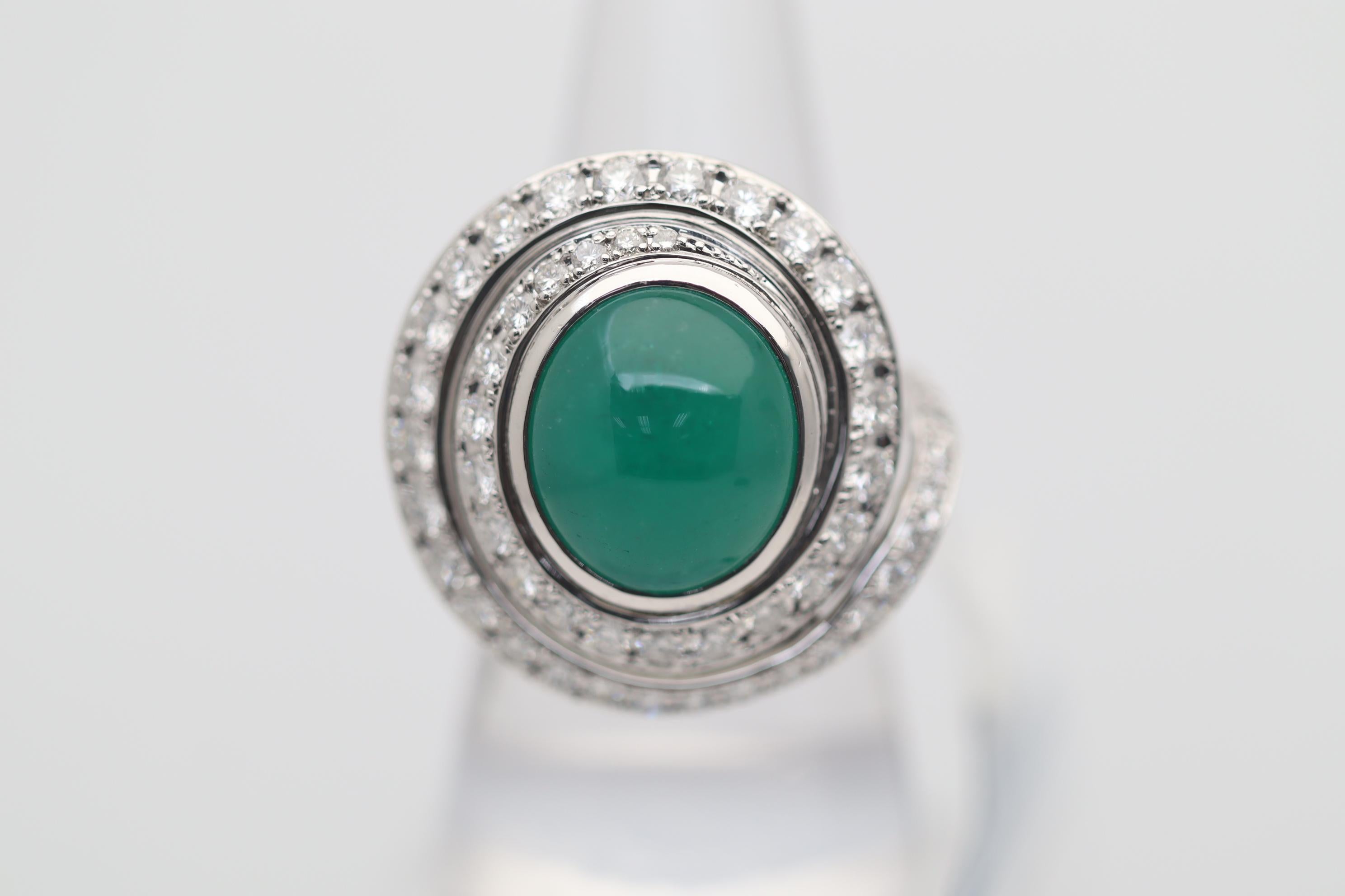 A large and impressive ring featuring a 8.59 carat cabochon emerald with an even deep green color. It is accented by 4.31 carats of round brilliant-cut diamonds set spiraling around the emerald as well as additional diamonds set on the underside of