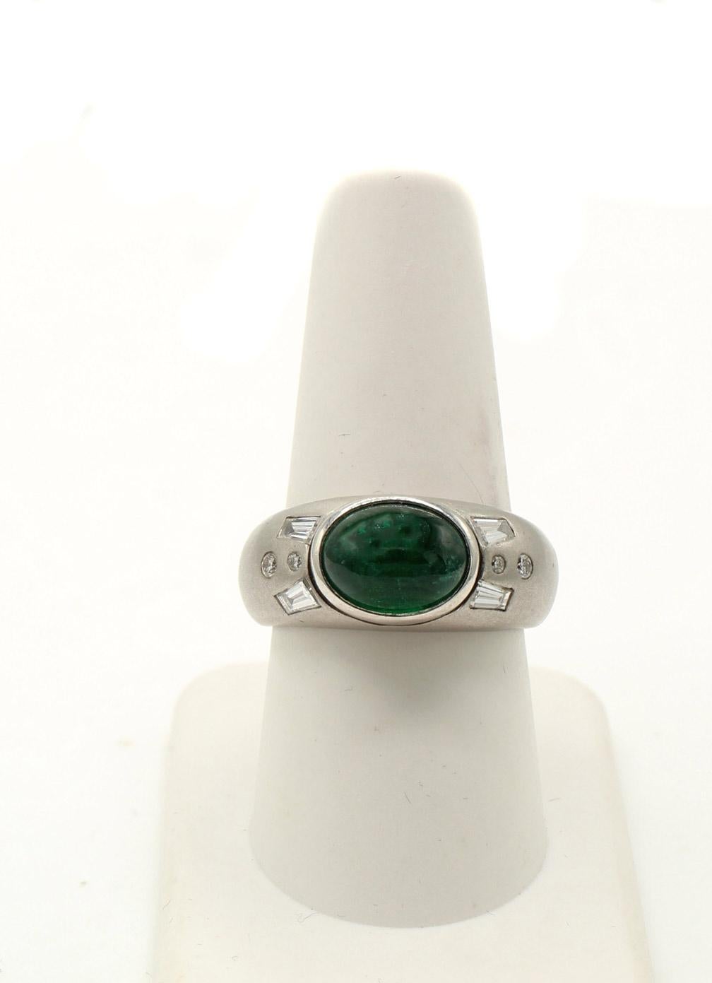 A beautiful deep green cabochon emerald weighing 3.67 carats is the center piece of this stunning platinum gypsy ring. The ring is further embellished by 2 baguette and 2 round brilliant cut diamonds on either shank. The weights are stamped on the
