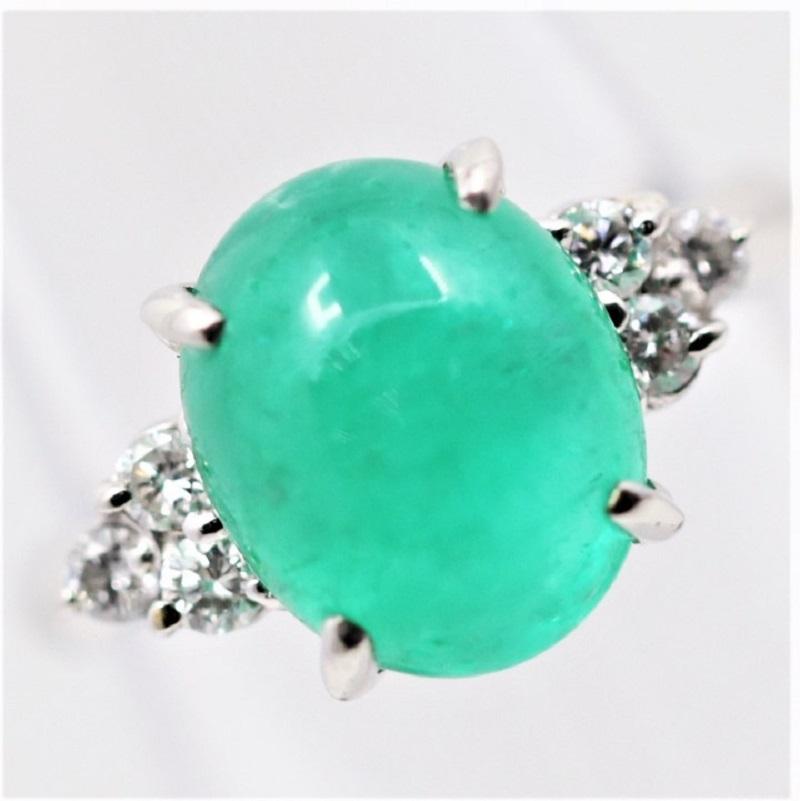 A lovely 4.12 carat cabochon emerald takes center stage. It has a rich royal “jelly-bean” green color that you will simply want to eat! It is accented by 6 round brilliant-cut diamonds set in a pair of clusters on its sides. Hand-fabricated in