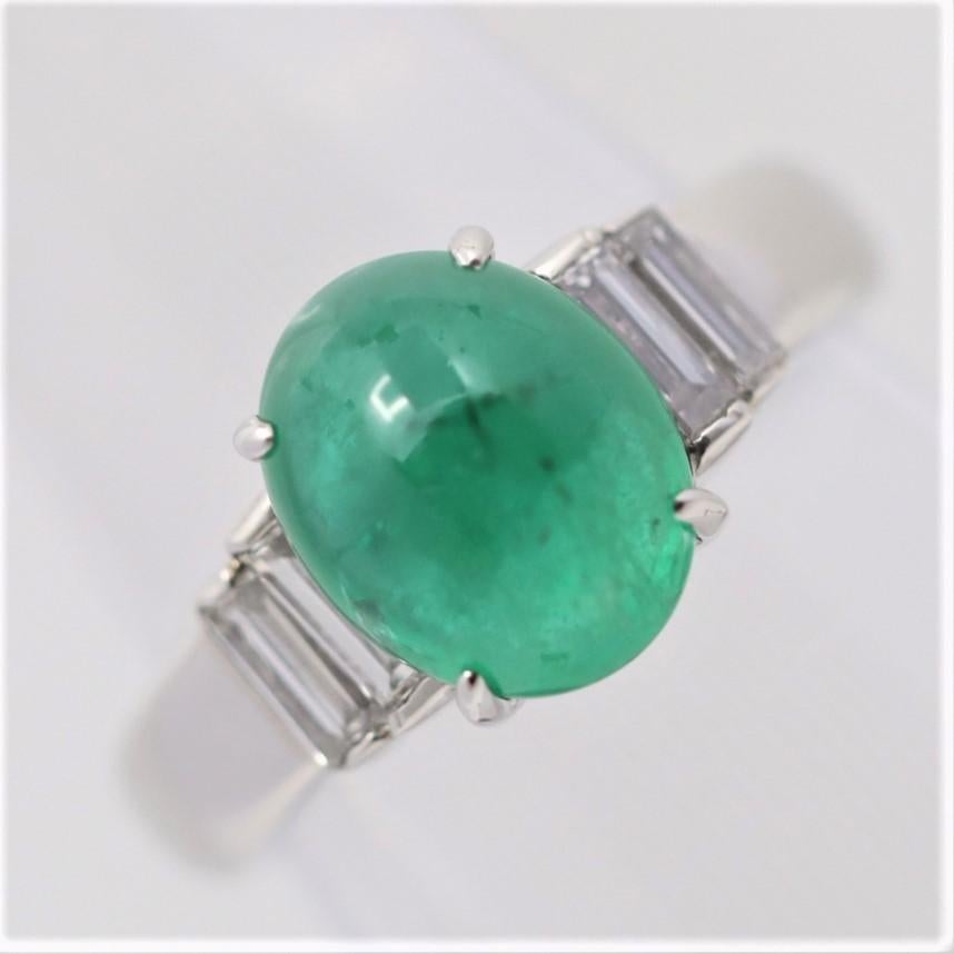 A lovely and simple platinum ring featuring a fine cabochon emerald weighing 3.06 carats. It has a rich and vibrant green color making us believe it has a Colombian origin. It is complemented by 0.55 carats of step-cut diamonds set on its two sides.