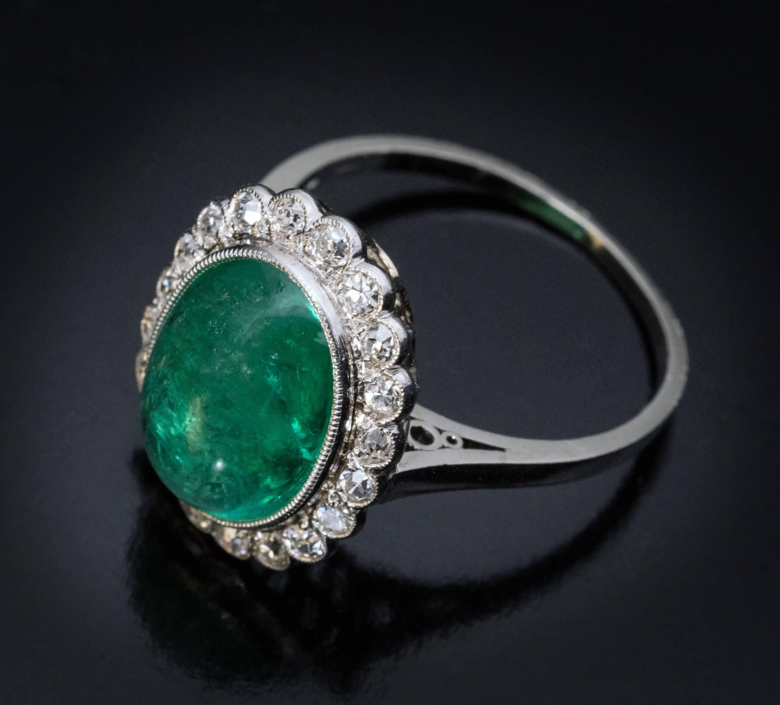 Made in Vienna, Austria, in the 1920s.  The platinum ring features a cabochon cut emerald of a glowing bluish green color, surrounded by bright white old cut diamonds.  The emerald measures 12.21 x 9.18 x 5.4 mm and is approximately 4.53 carats. 