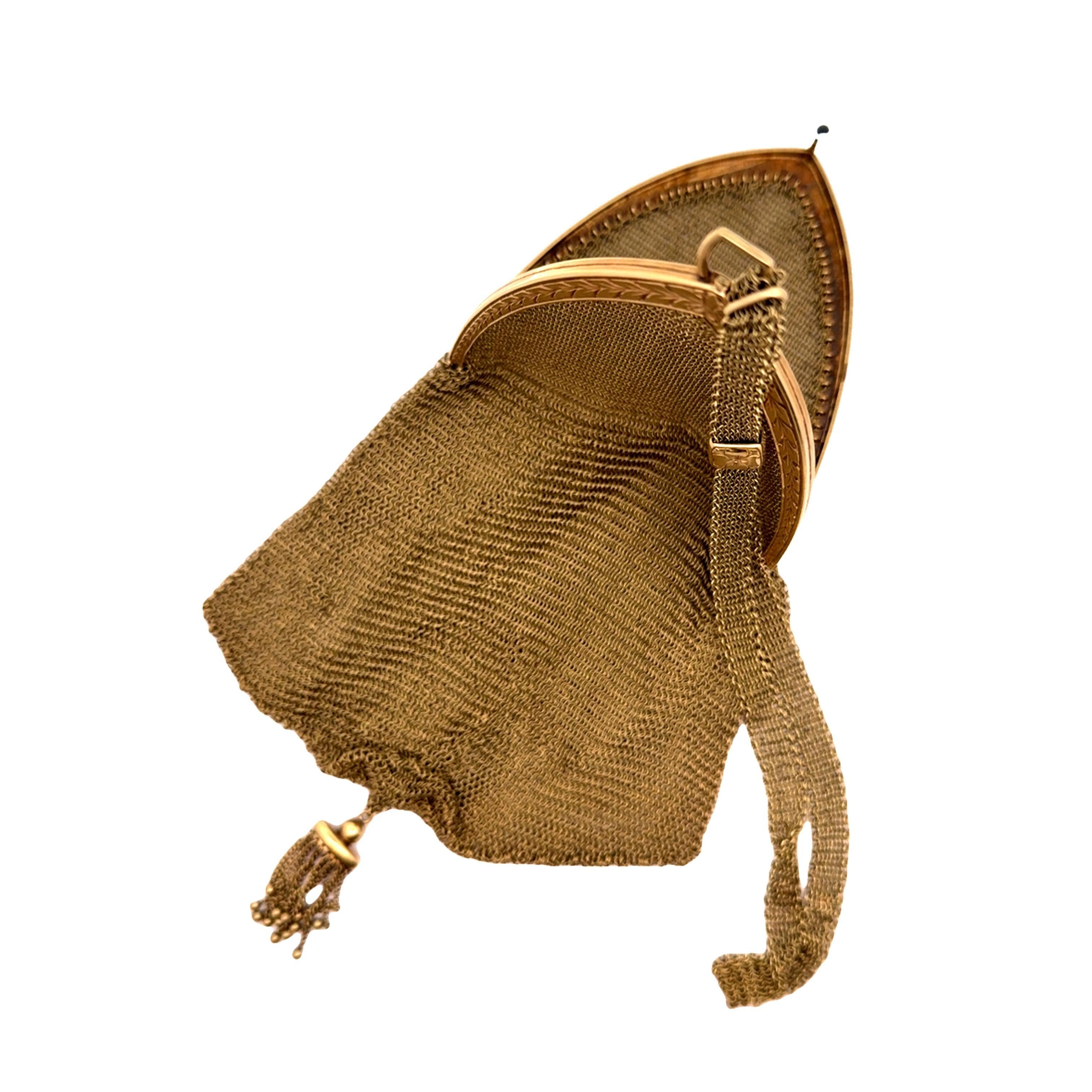 Un'accattivante borsa da sera a rete realizzata in oro giallo 14 carati. La borsa presenta un intricato design a maglia, che emana un fascino lussuoso e senza tempo. La cornice è impreziosita da un delicato motivo inciso e da uno smeraldo cabochon