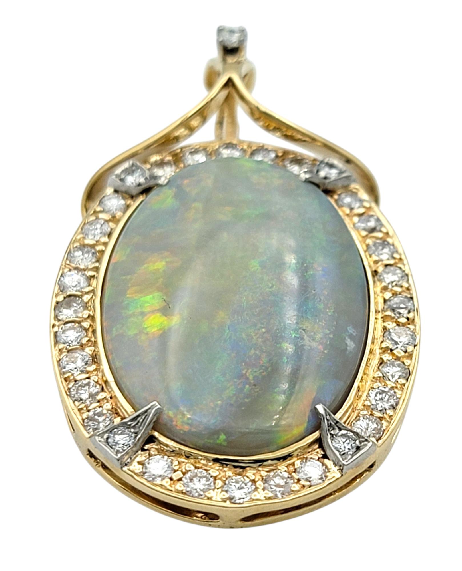 Ce pendentif rehausseur saisissant met en valeur un cabochon d'opale grise de forme ovale et lumineuse, serti dans une combinaison d'or jaune et d'or blanc 14 carats. Le corps translucide de l'opale révèle un jeu de couleurs multicolores vibrant qui