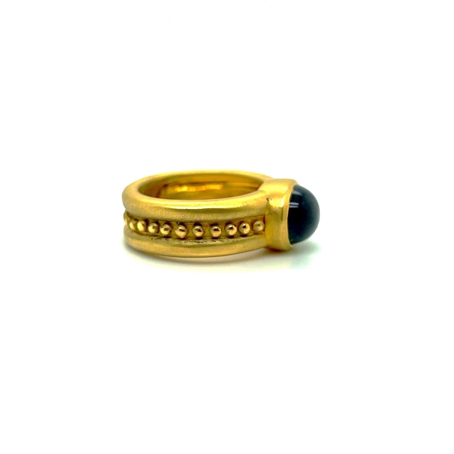 An 18 karat yellow gold ring designed with an oval cabochon green tourmaline center. The stone is set east /west on a matte shank detailed with gold beads.
Stamped 750
Finger size 6.5