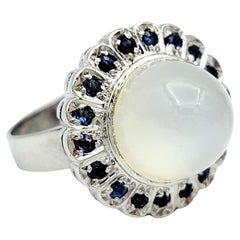 Anello da cocktail con pietra di luna cabochon e zaffiro aureolato in oro bianco 10 carati