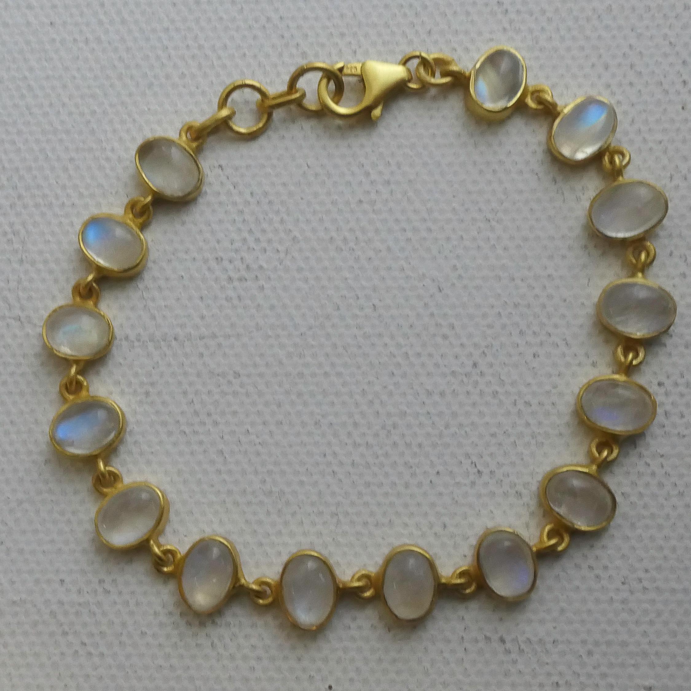 Delicada y soñadora, esta pulsera presenta cabujones ovales de 4x6 mm de piedra lunar arco iris natural, cada uno de los cuales brilla con una suave iridiscencia que atrapa la luz en tonos azules y blancos. Conocida por su energía calmante y su